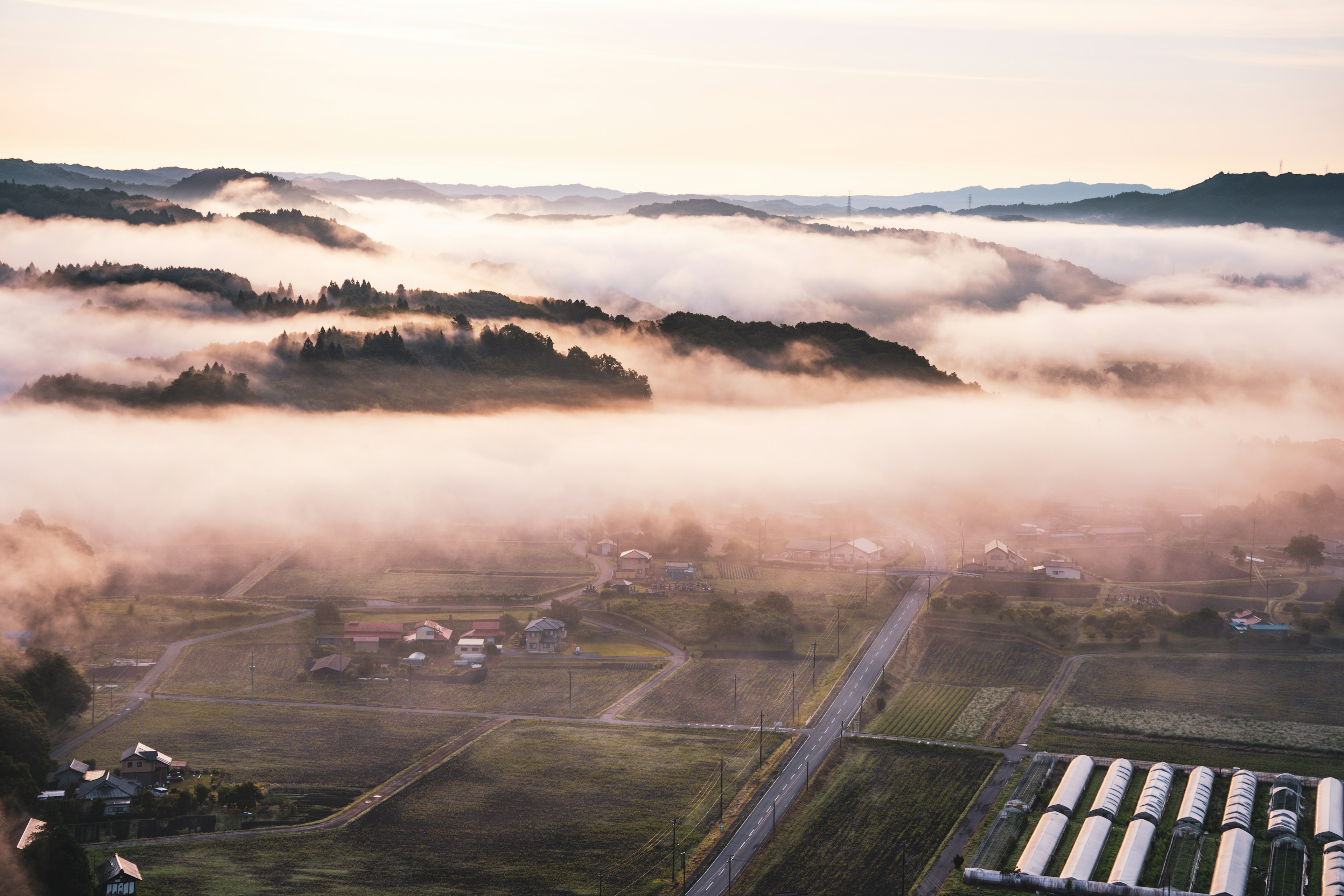 Aerial view of a misty rural landscape with rolling hills