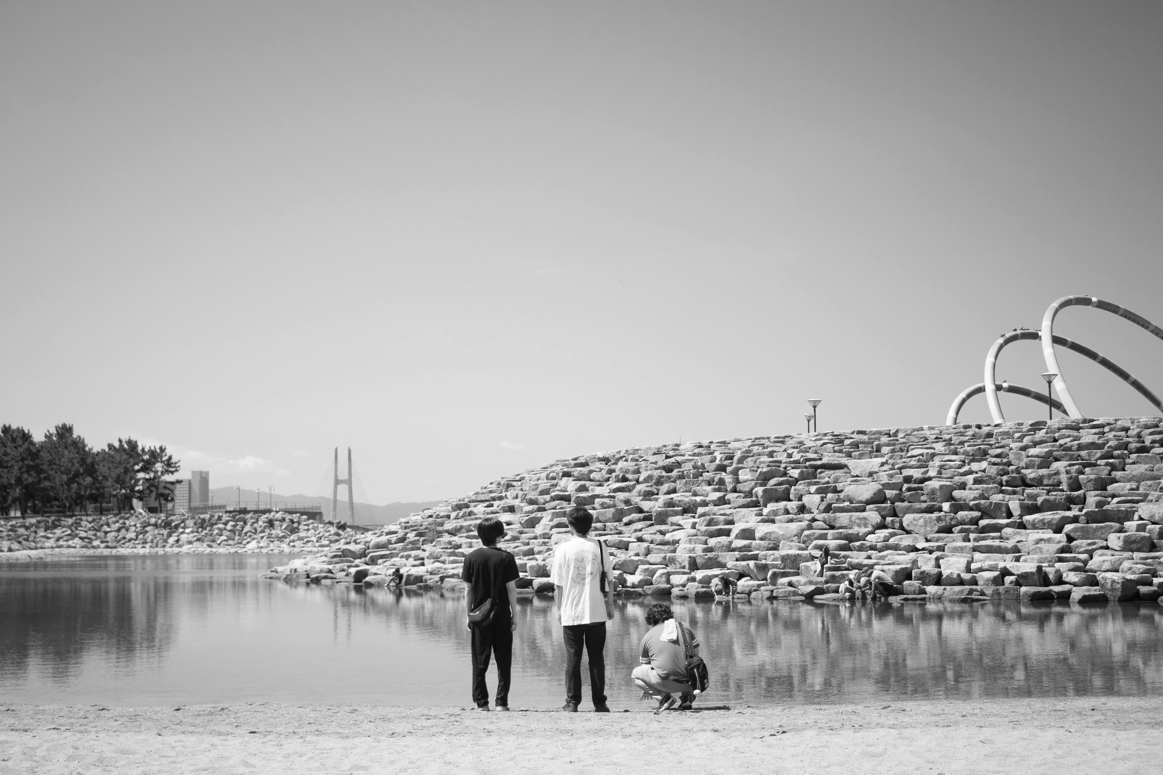 Famille se tenant près de l'eau dans un paysage en noir et blanc