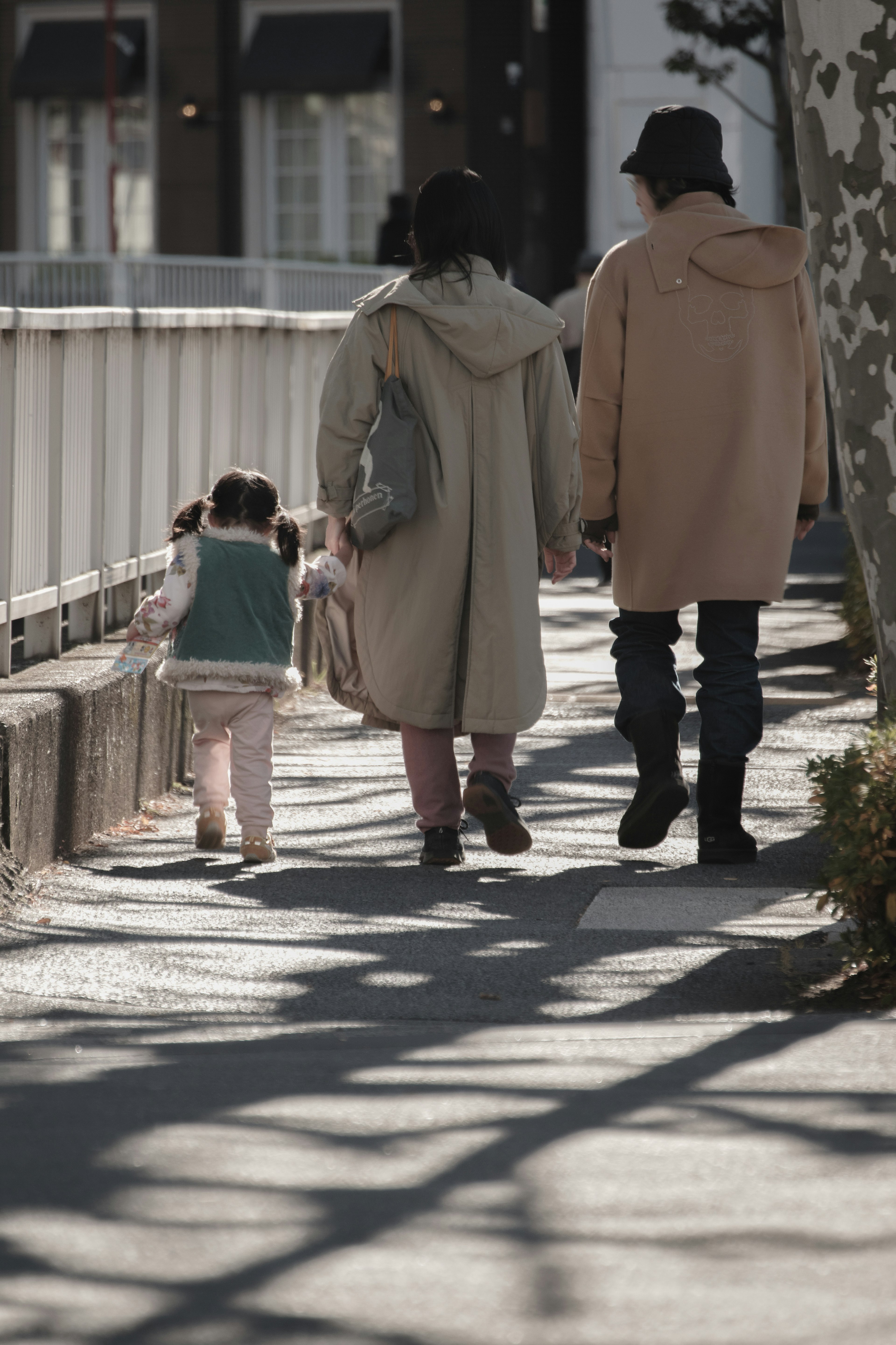 Family walking together on a sunny day with shadows casting on the path