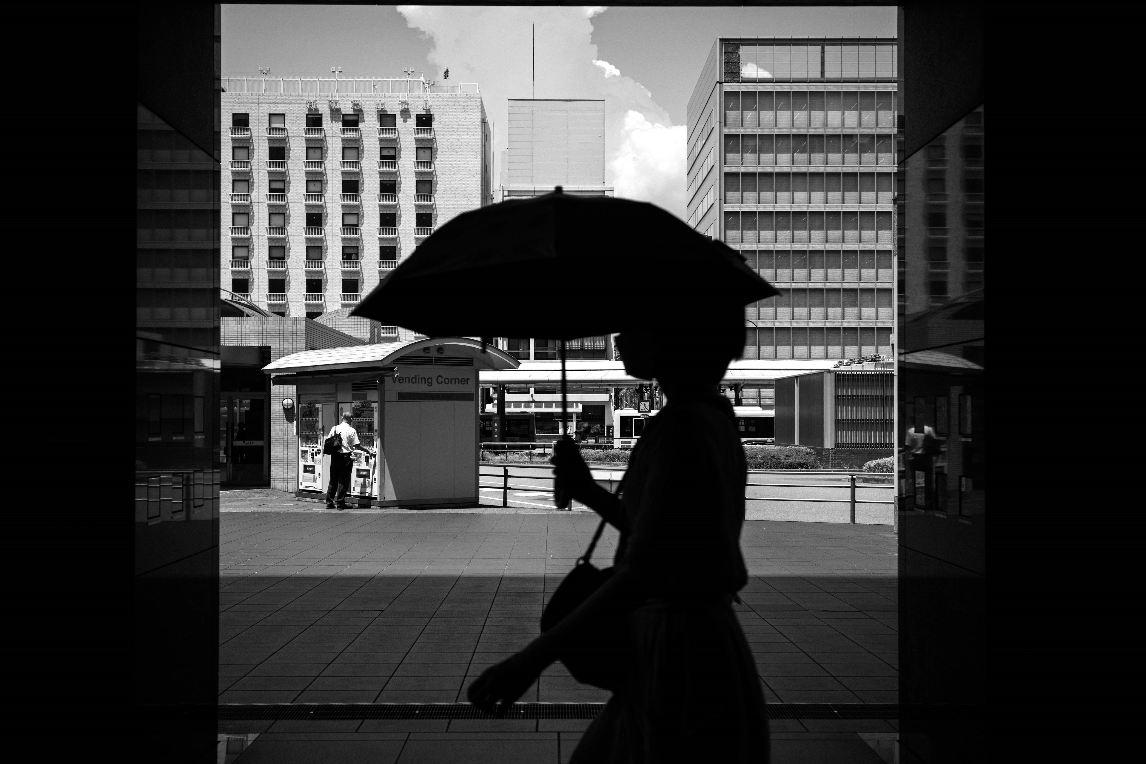 Silhouette d'une femme tenant un parapluie contre un paysage urbain en monochrome