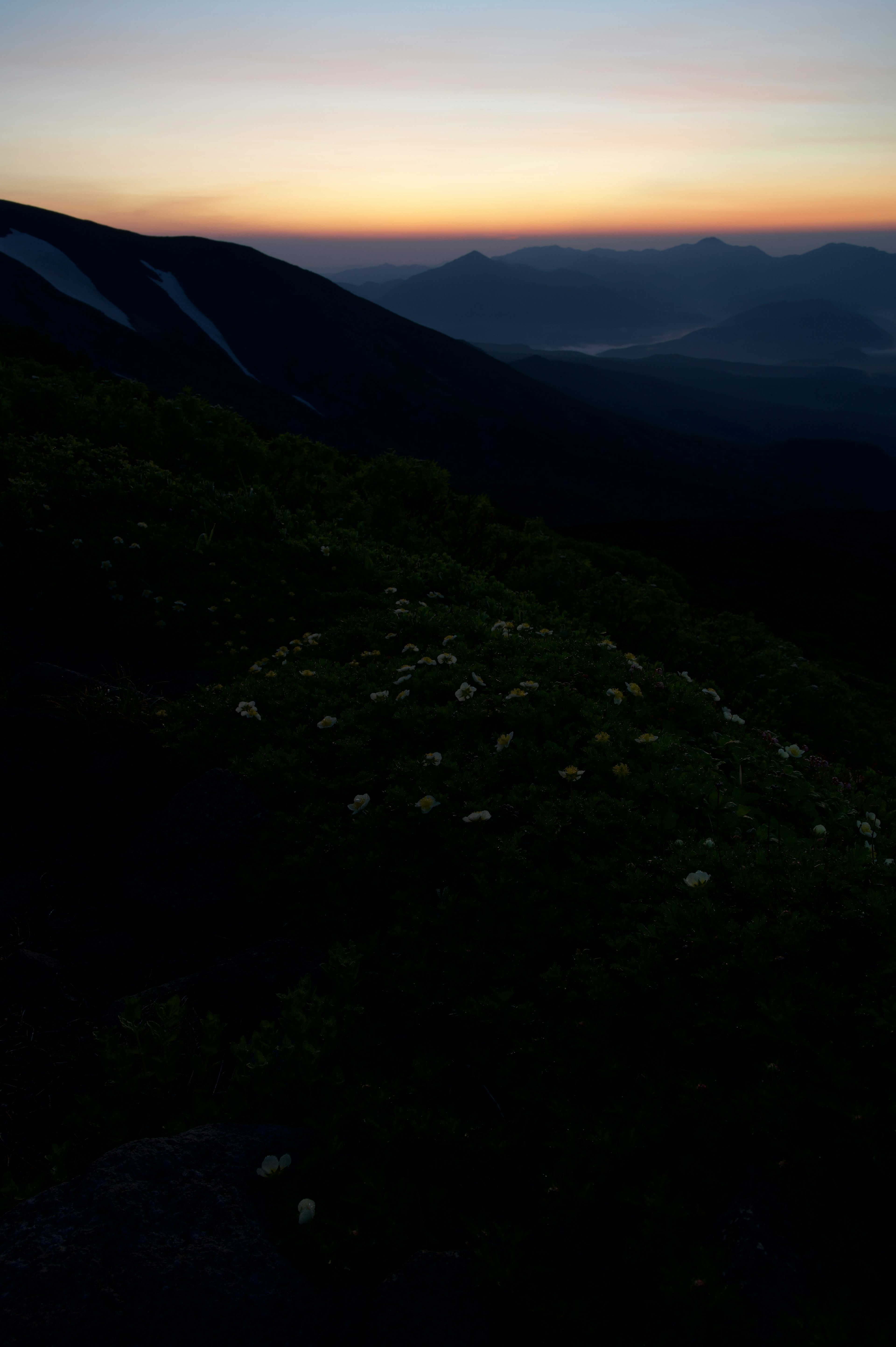 Mountain landscape at dusk featuring green grass and distant mountains