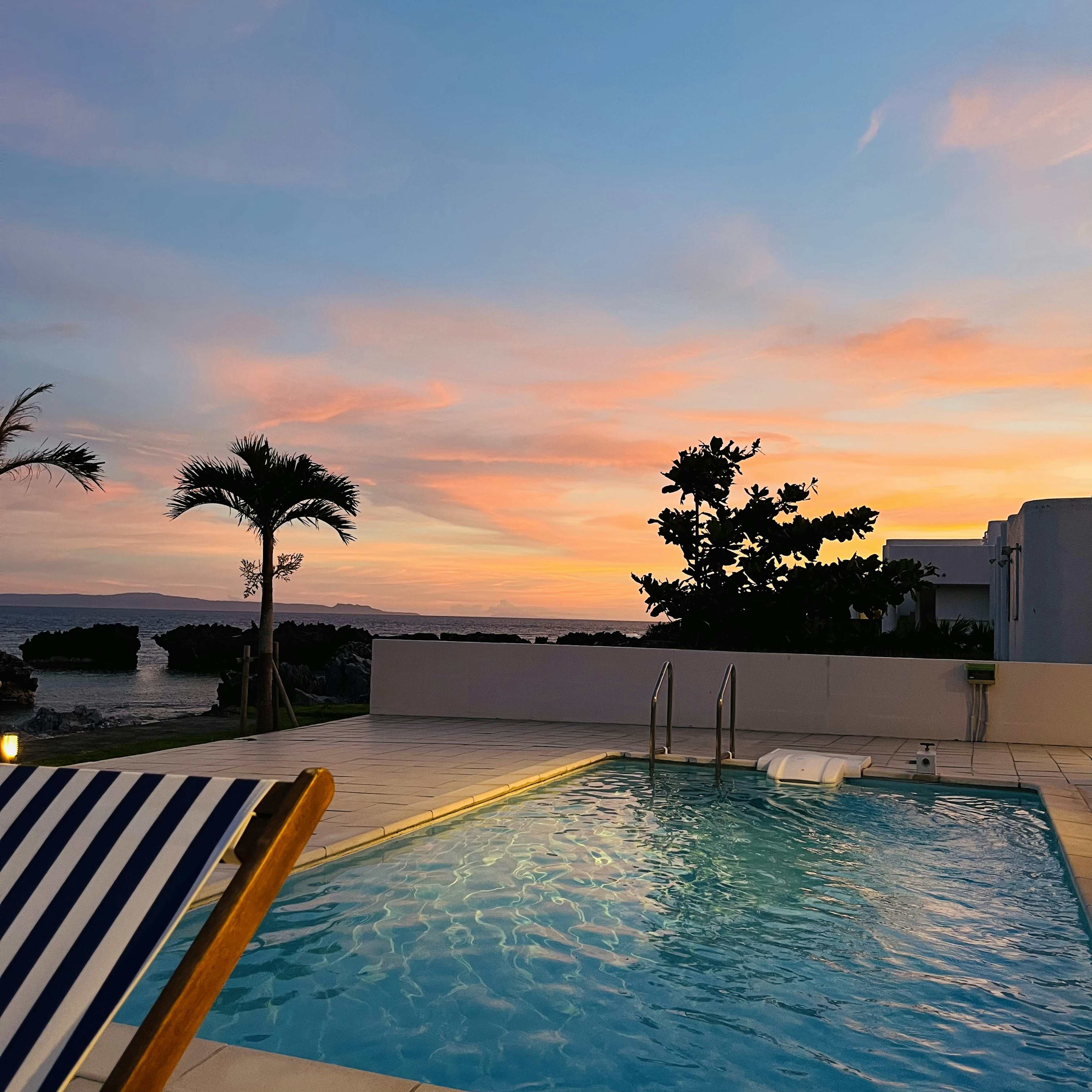 Relaxing poolside view with a blue pool and a colorful sunset sky