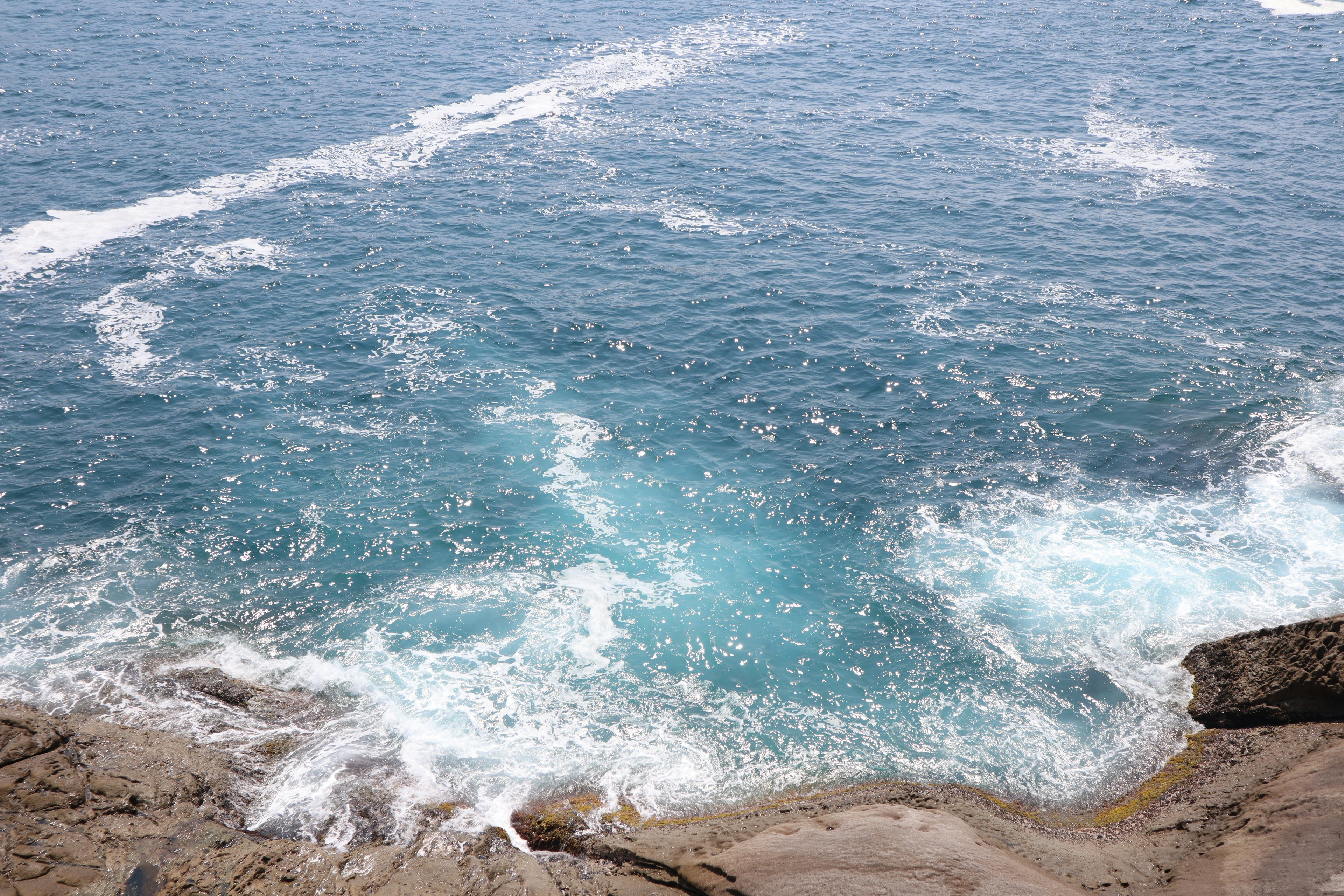 Olas oceánicas azules y costa rocosa