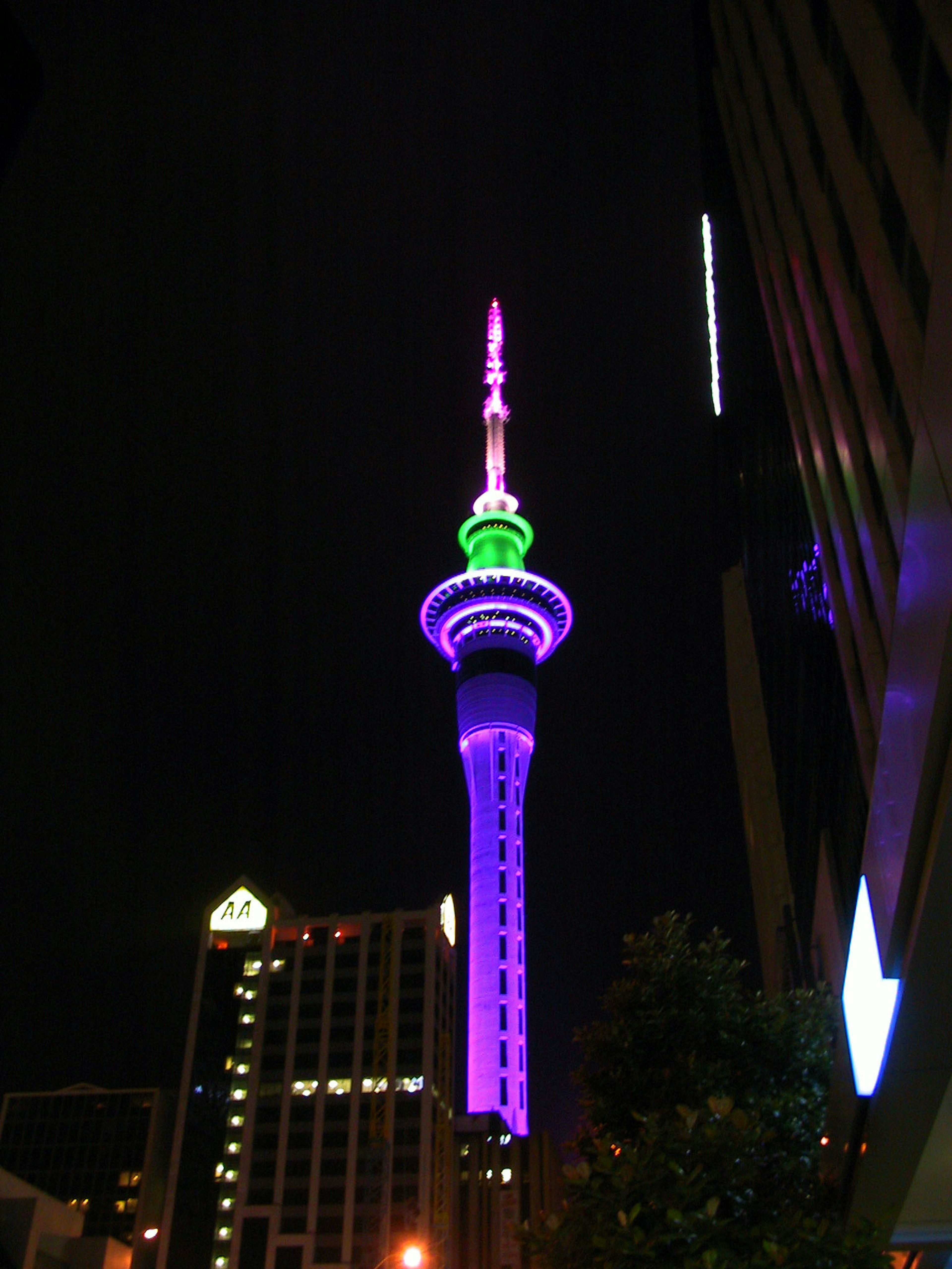 Sky Tower iluminada por la noche con luces moradas y verdes