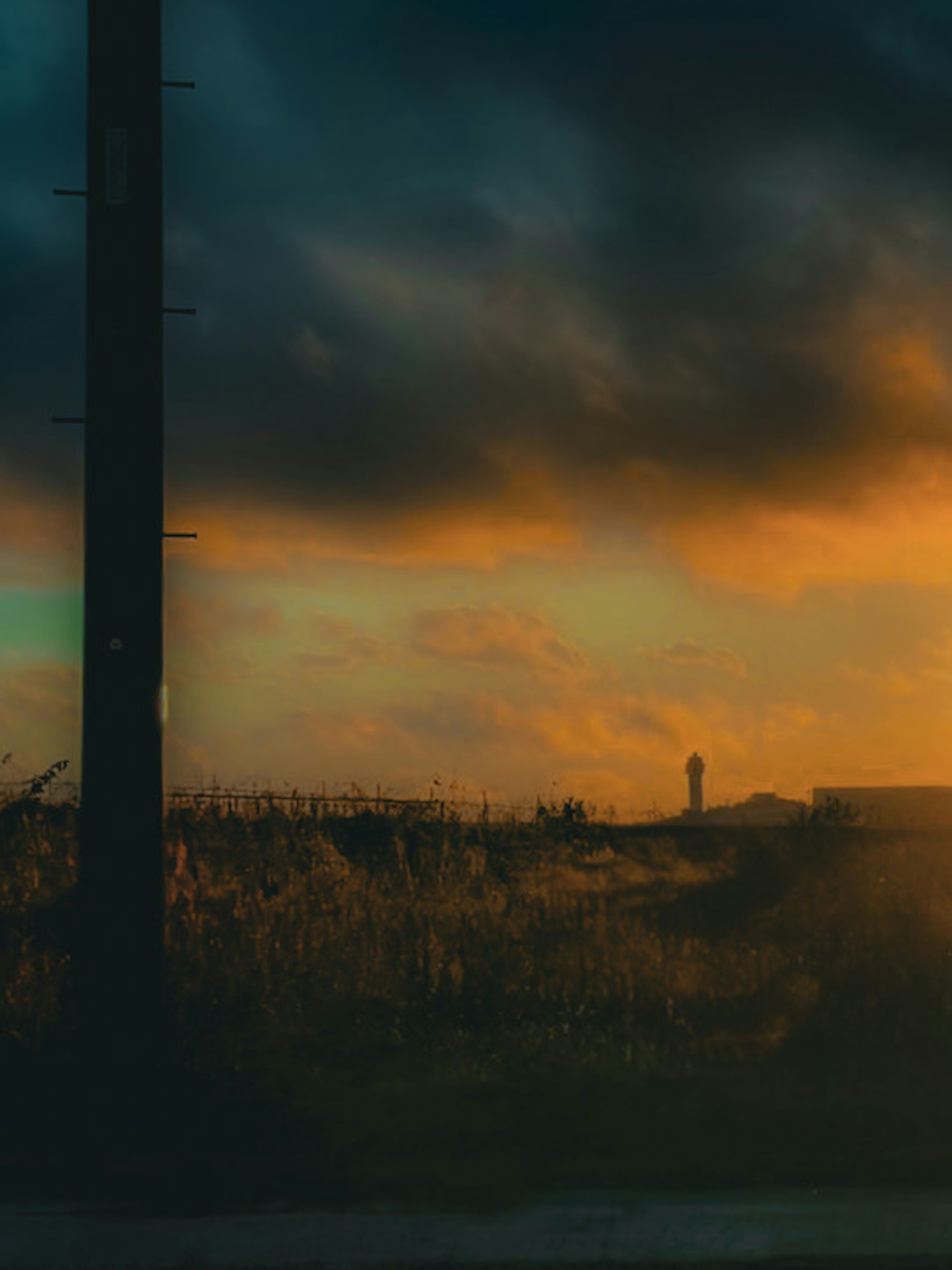 Silueta de un poste de luz y una persona contra un cielo al atardecer