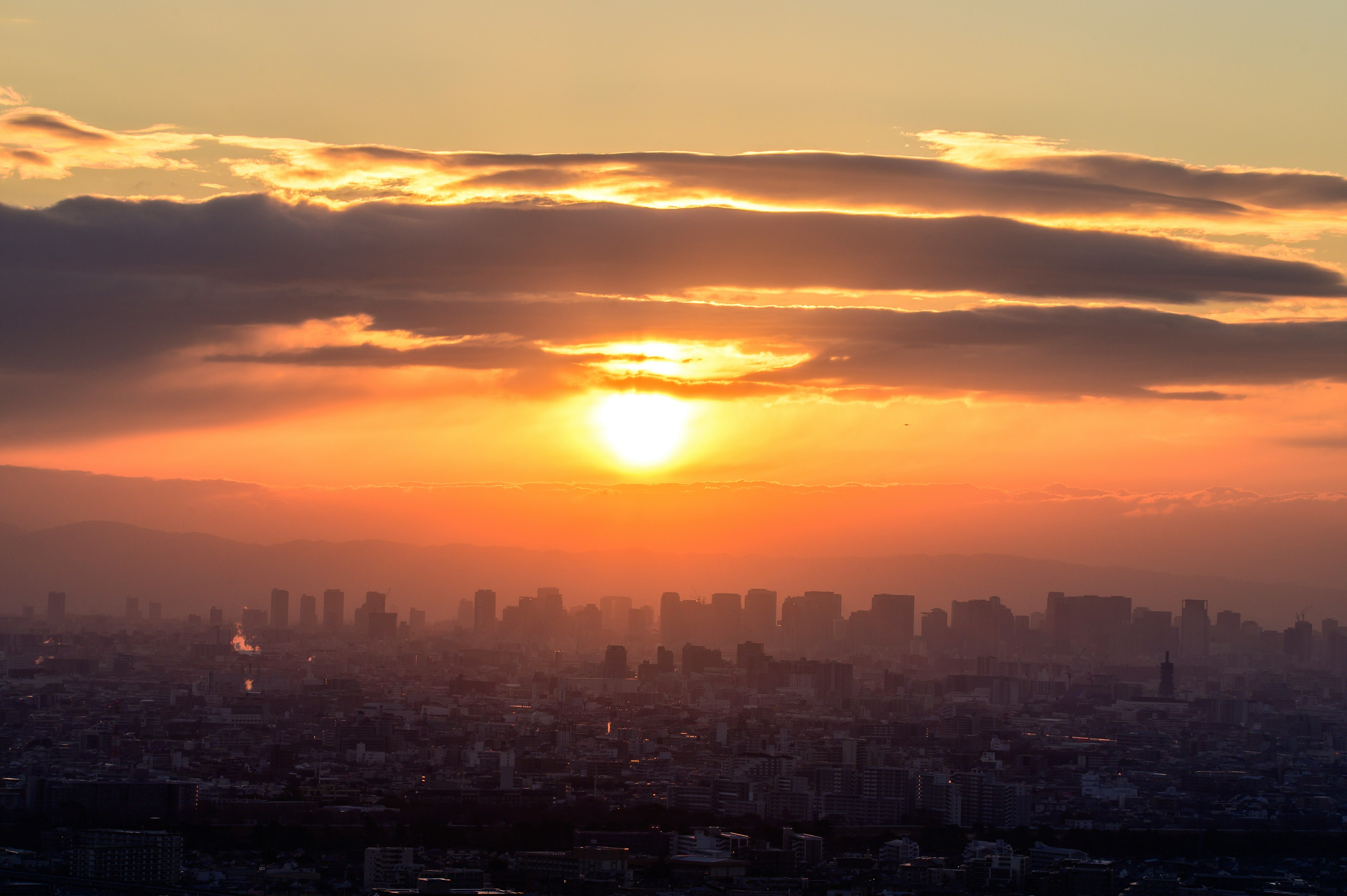 Silhouette de la ville au coucher du soleil avec des nuages et des rayons de lumière