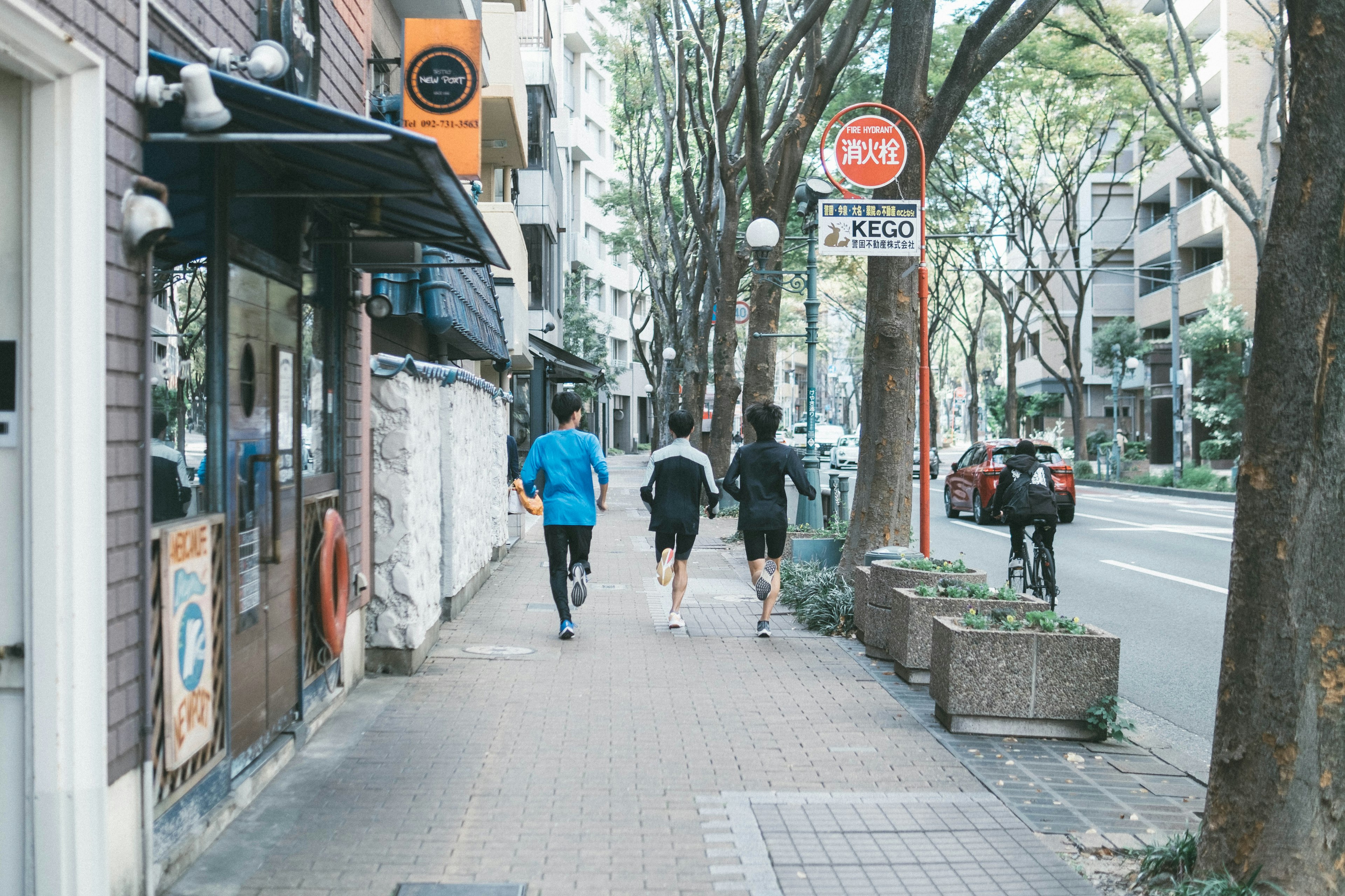 青いシャツを着た男性たちが歩道を歩いている都市の風景