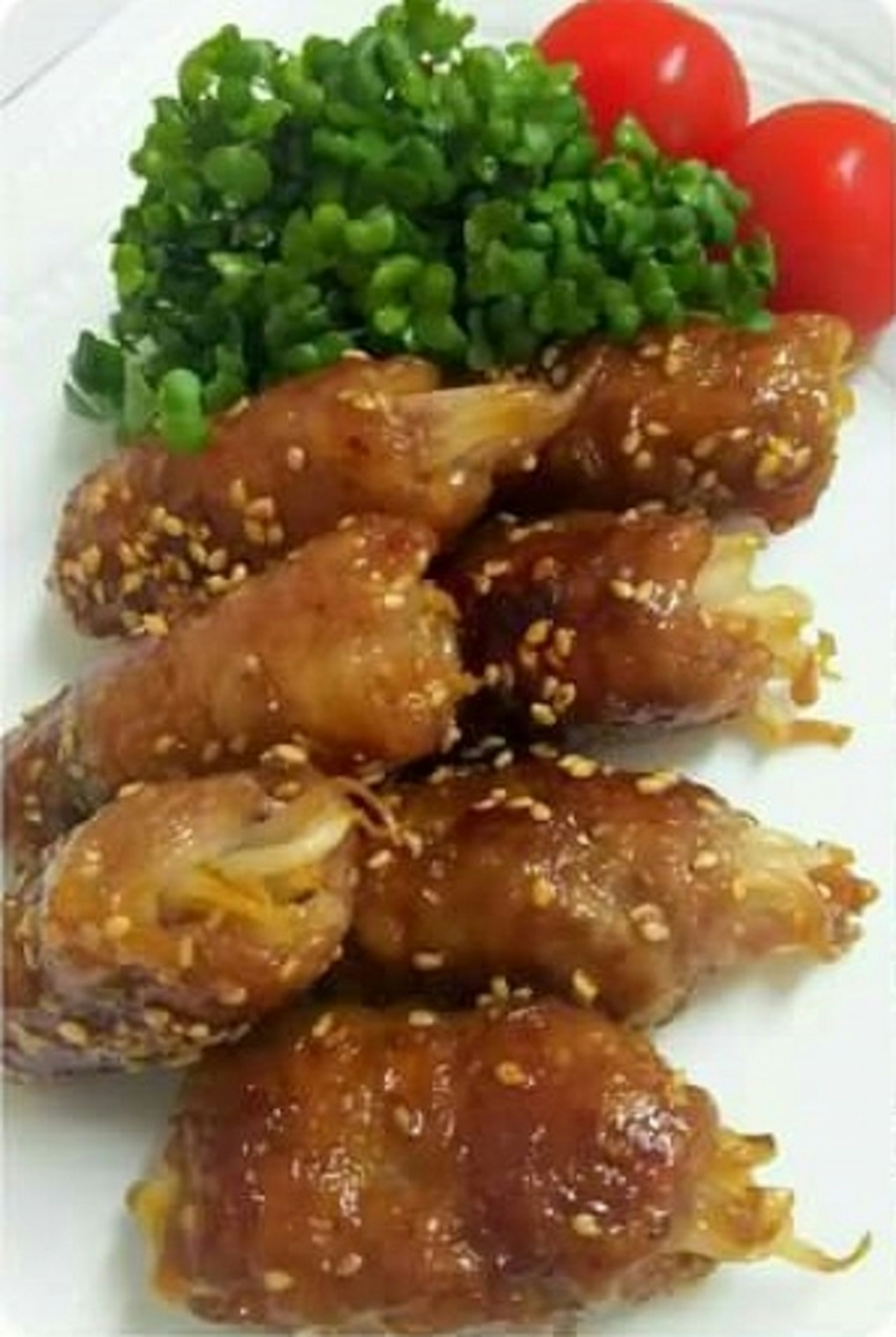 A plate of crispy fried rolls garnished with sesame seeds and fresh green vegetables