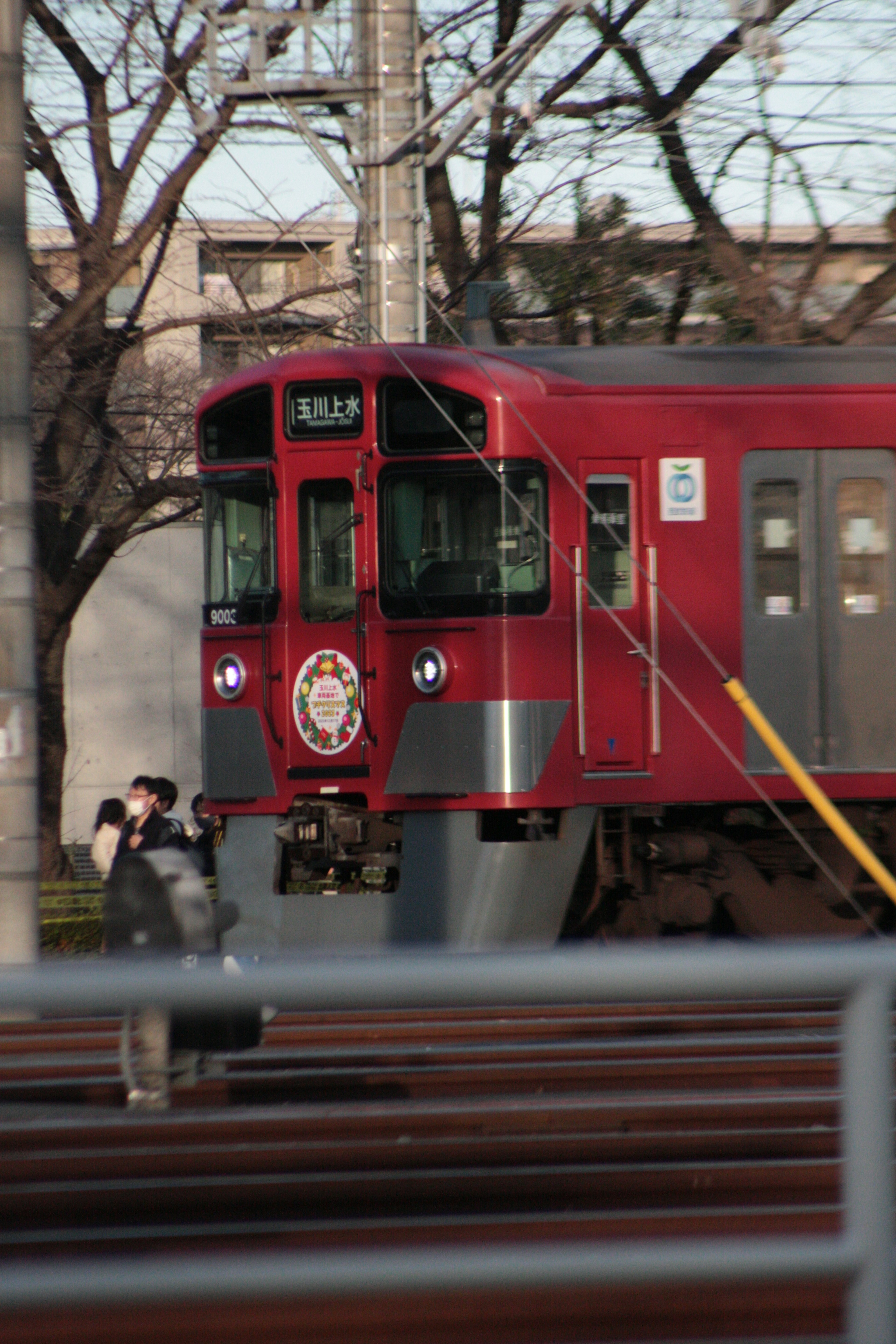 A red train stopped on the tracks with a person holding a camera