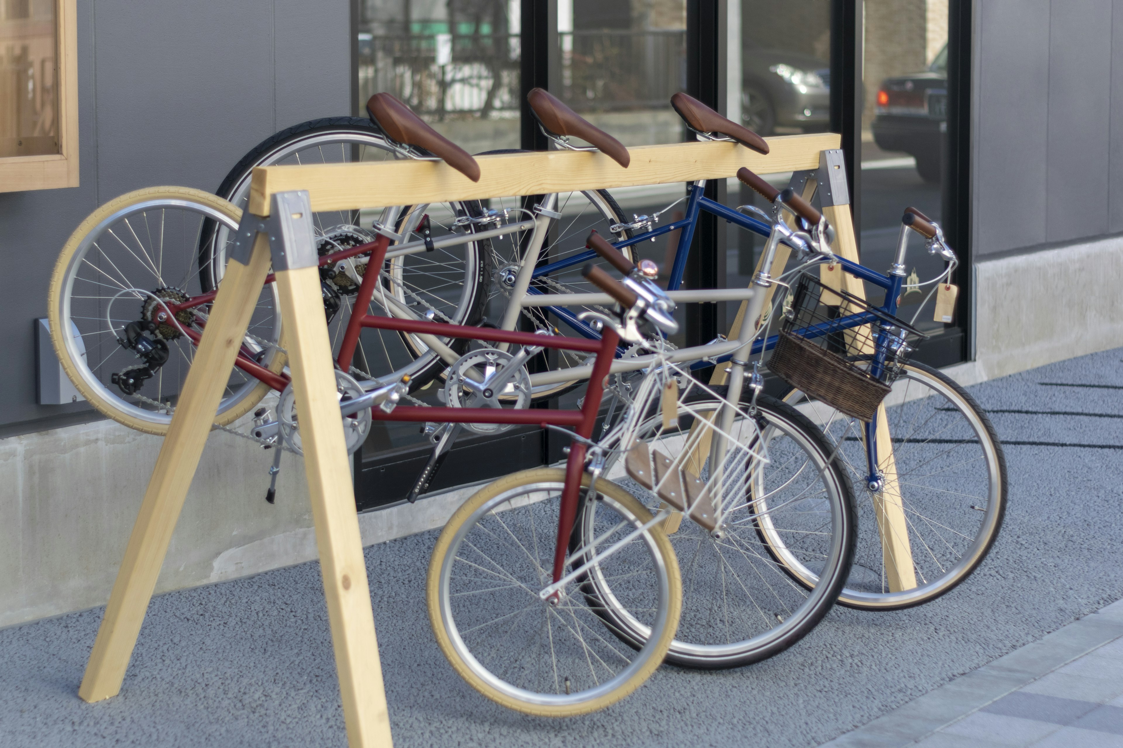 A row of red and blue bicycles parked on a wooden bike rack