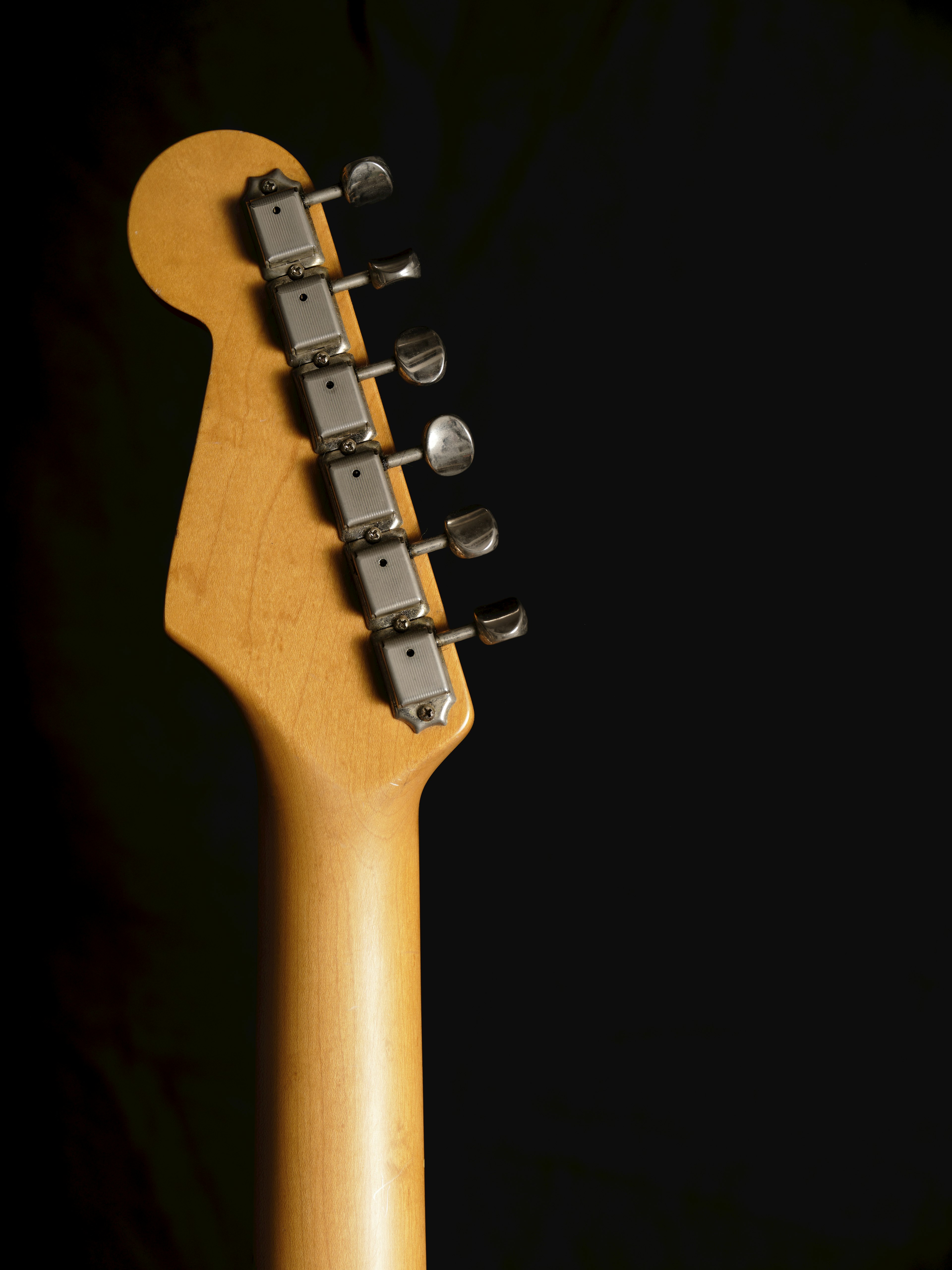 Side view of a guitar headstock with tuning pegs