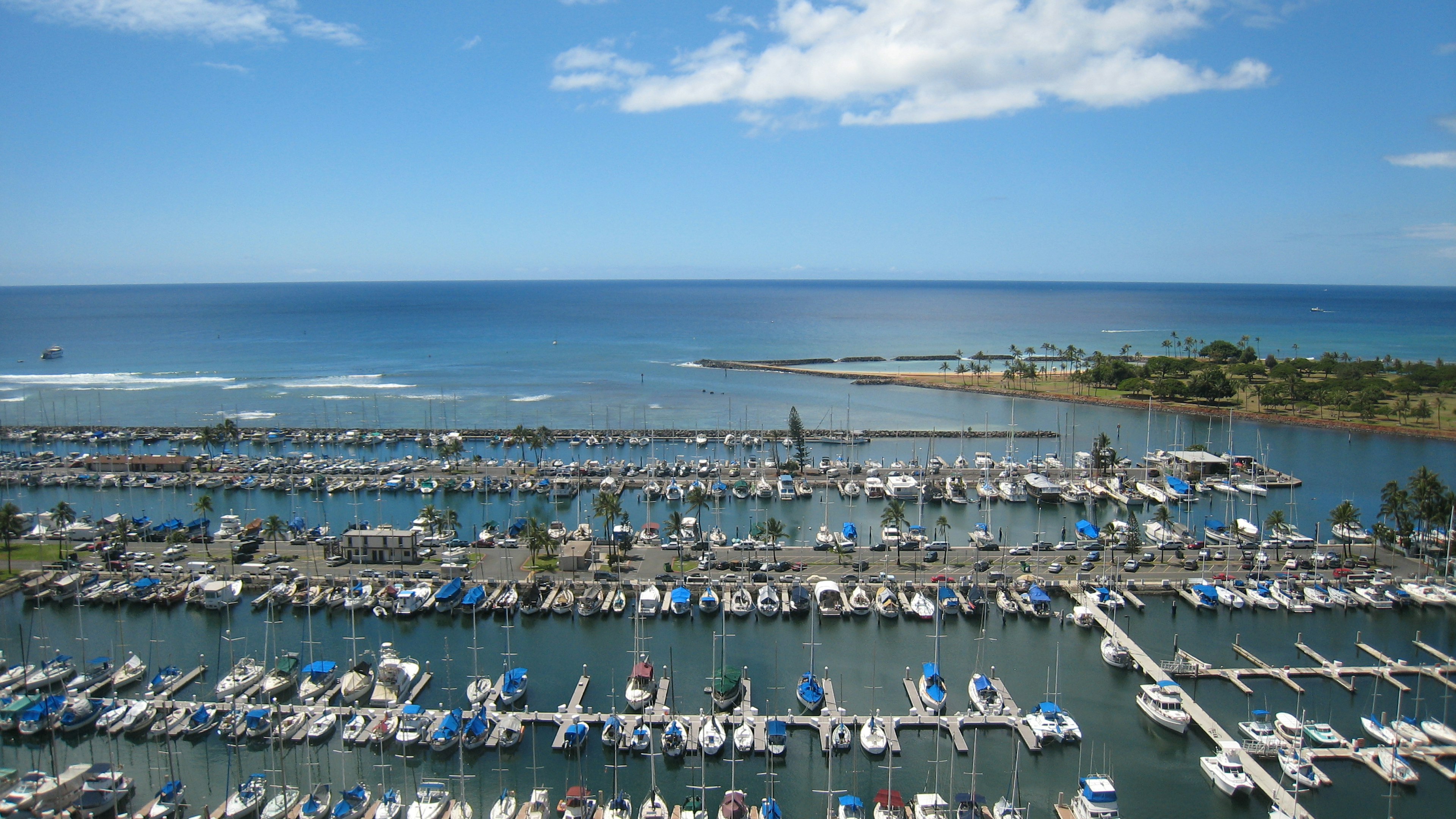 Un port de plaisance rempli de bateaux et de yachts sous un ciel bleu et un océan