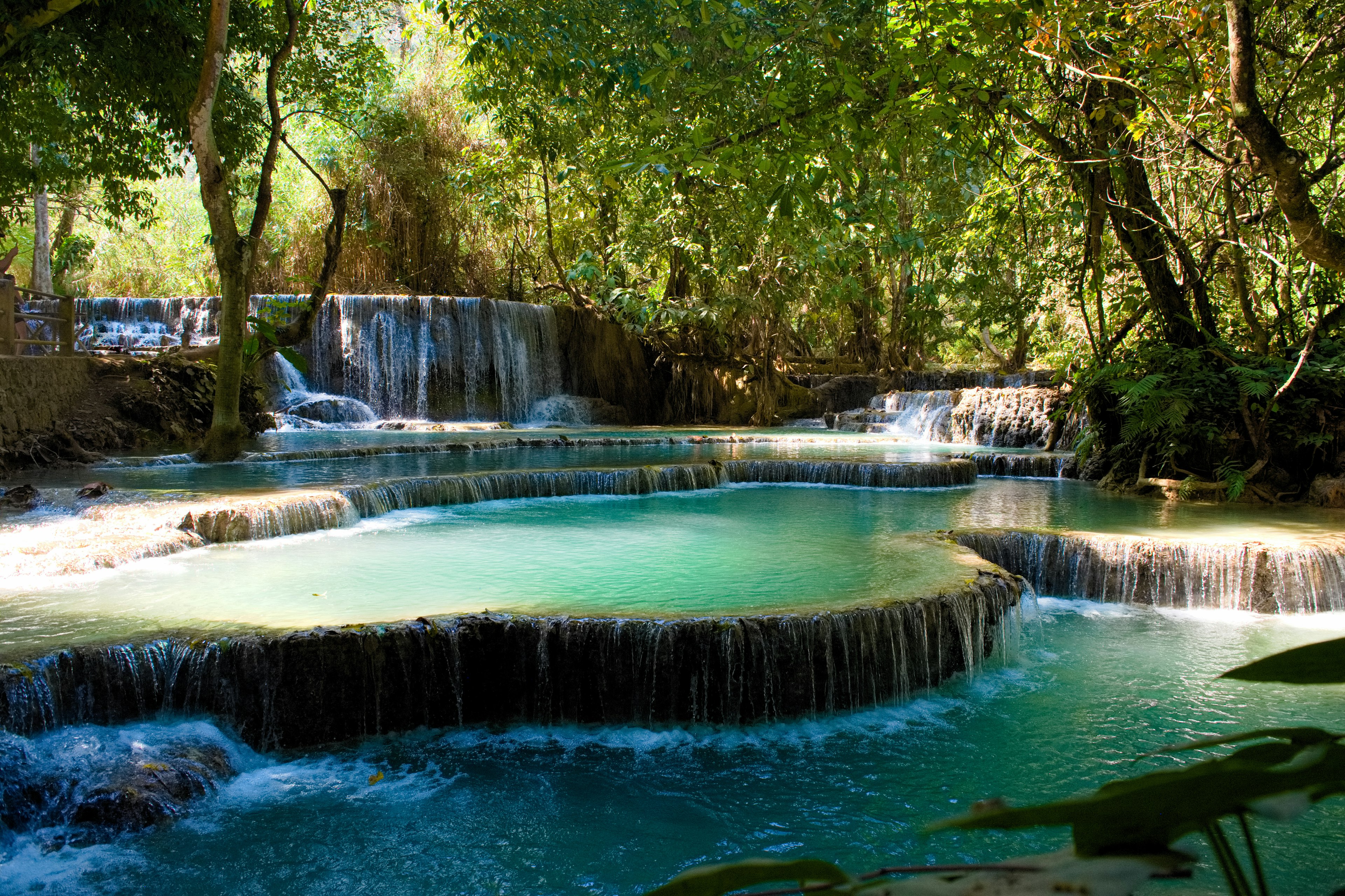 Air terjun indah dengan kolam berwarna turquoise dikelilingi oleh vegetasi subur