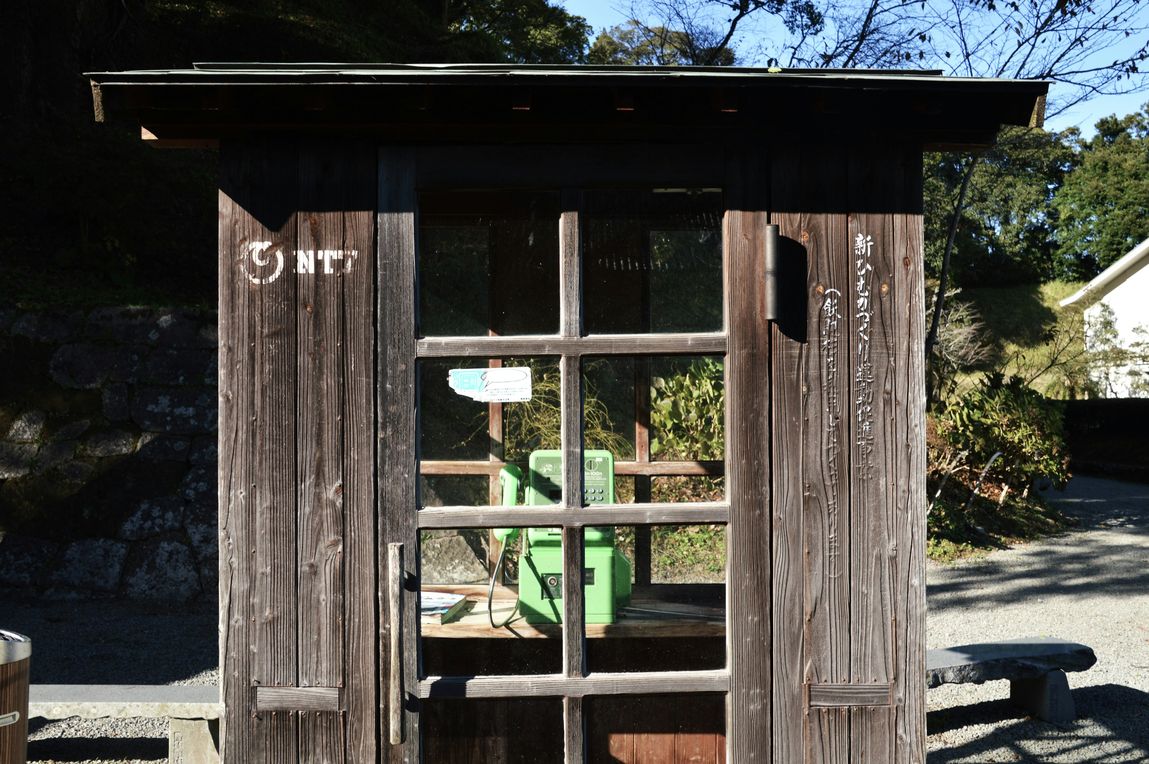 Old wooden phone booth with a green chair visible inside