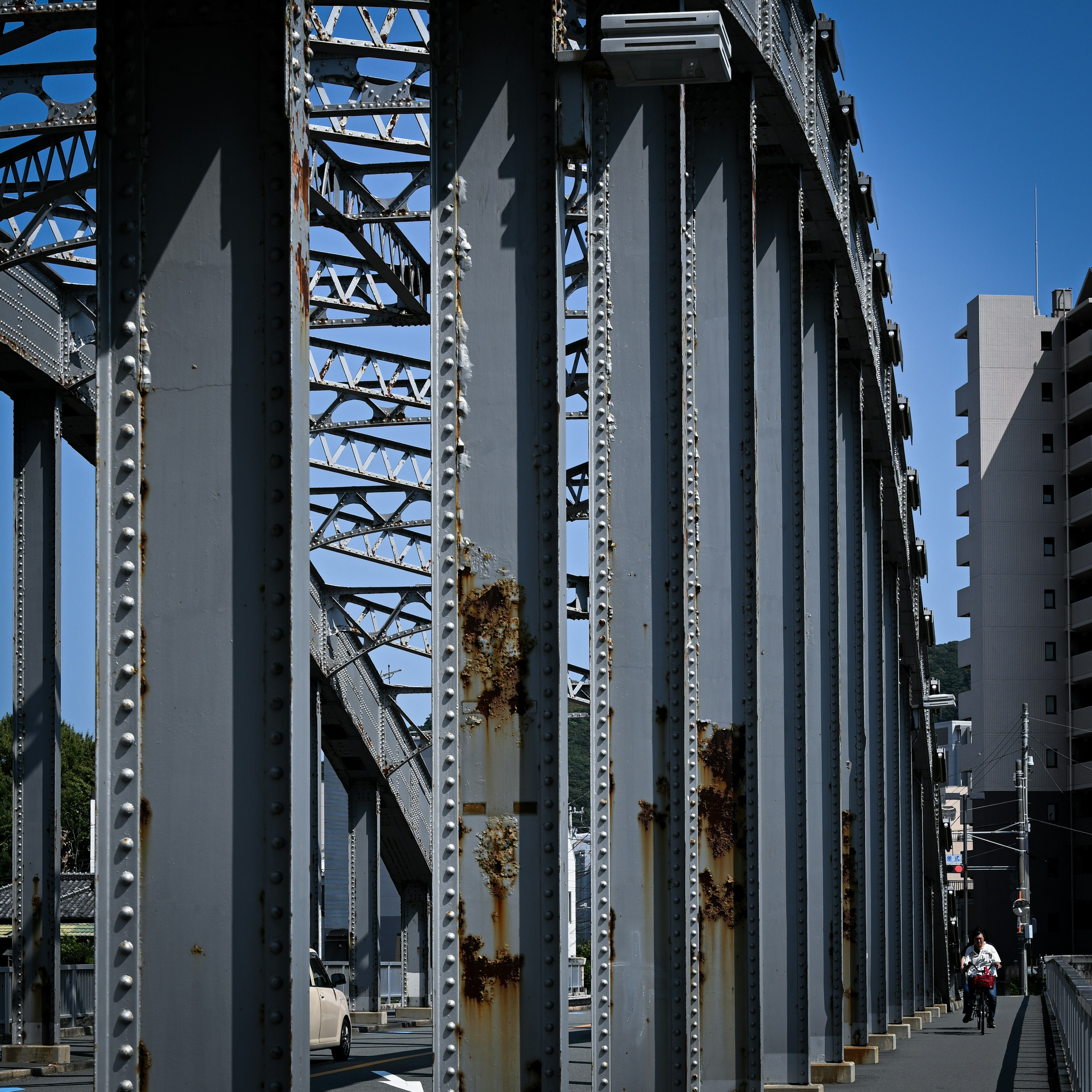 古い鉄橋の構造と青空の下の歩行者