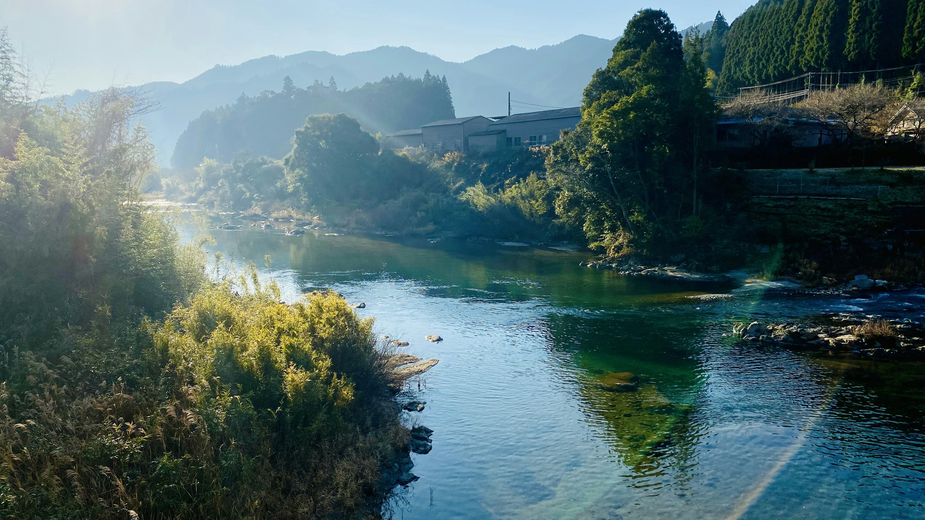 静かな川と山々の風景、青い水と緑の木々が映える