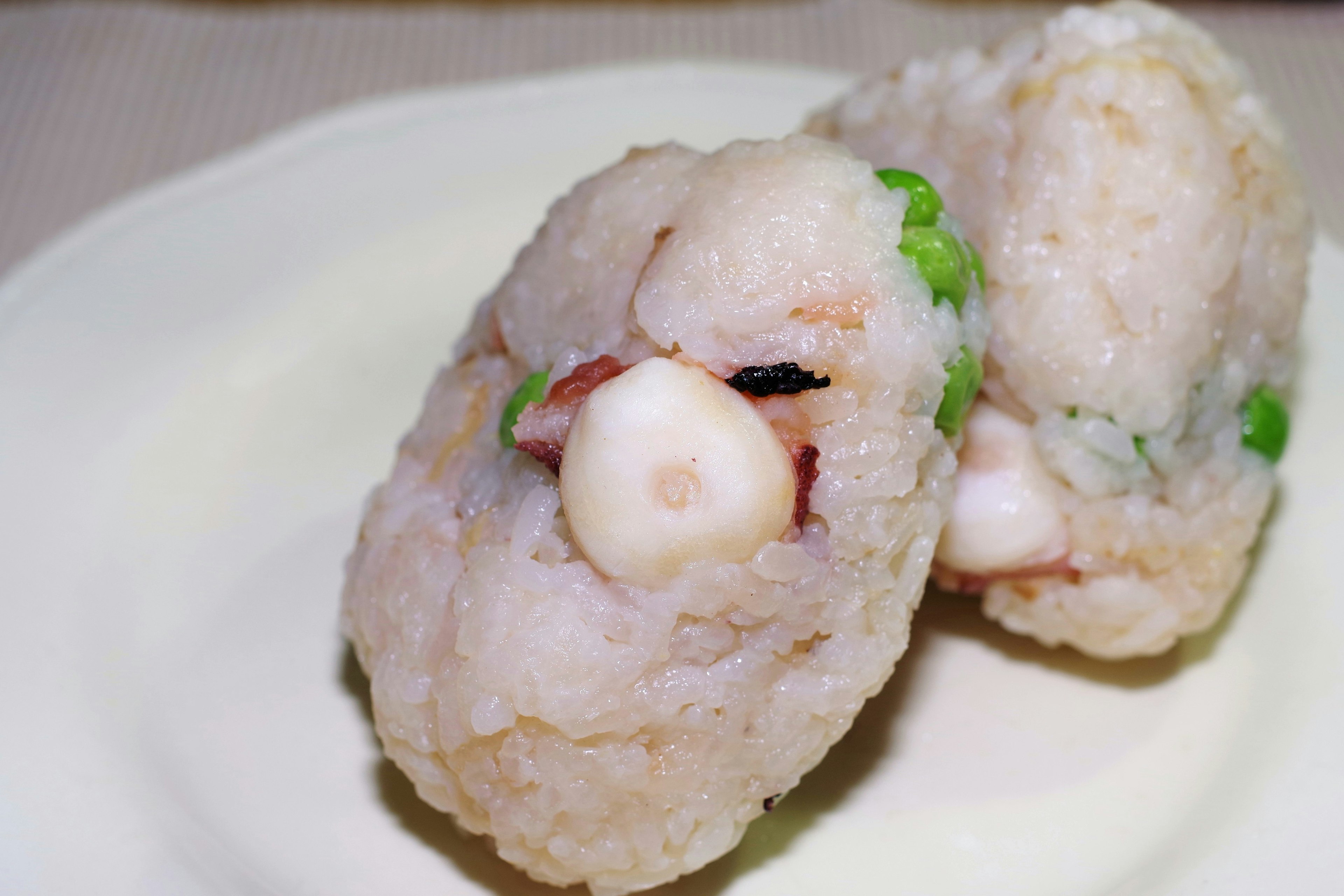 Two rice balls on a plate with visible seafood ingredients