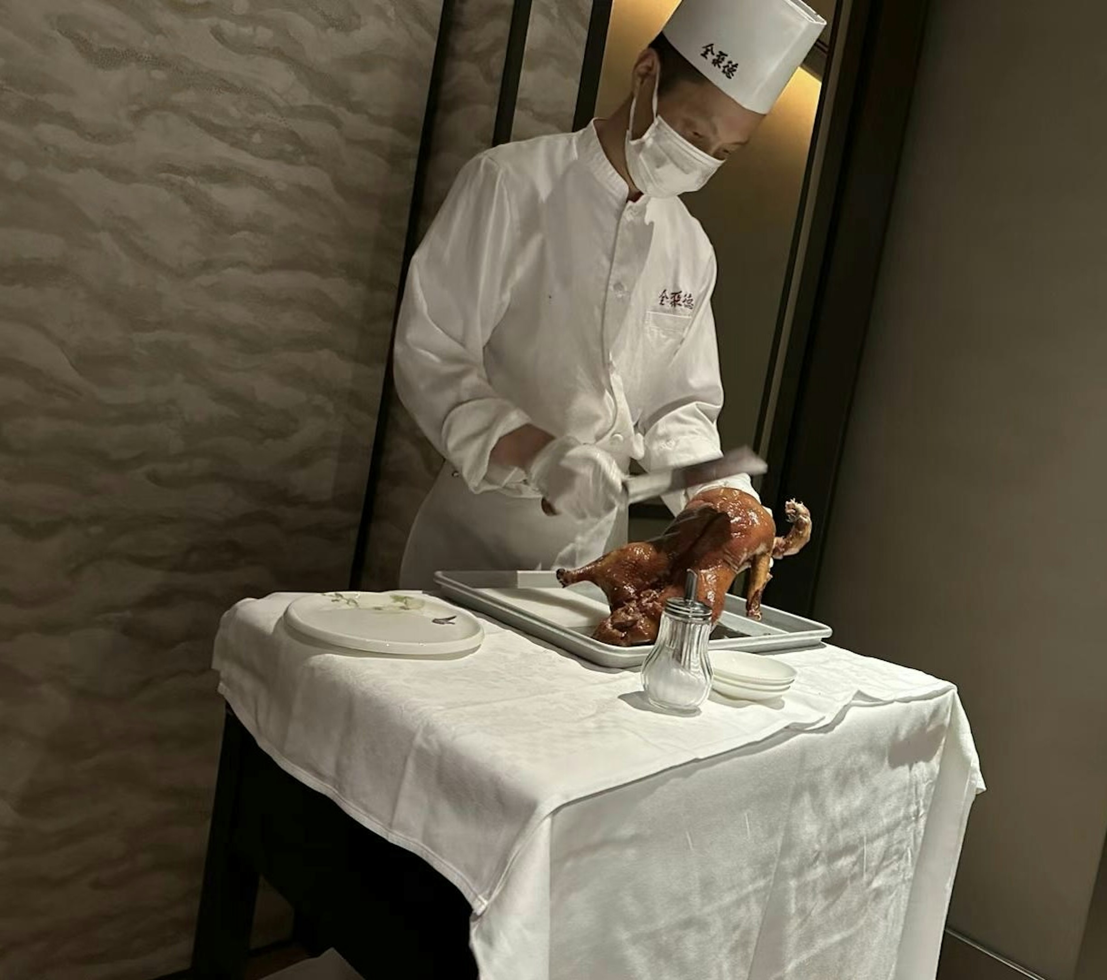 Chef découpant un canard rôti à une table de restaurant