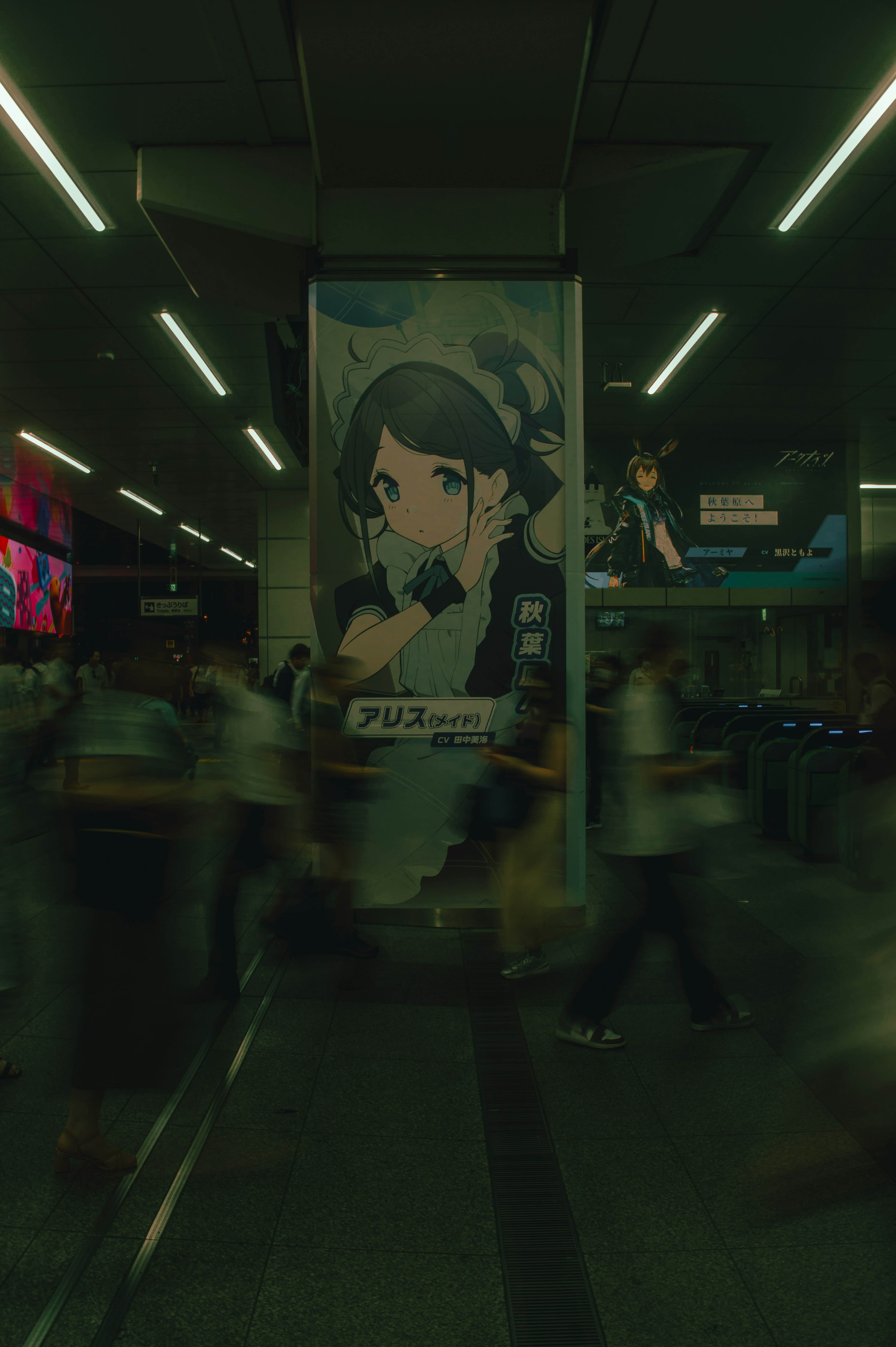 A busy station with a prominent character poster in the background