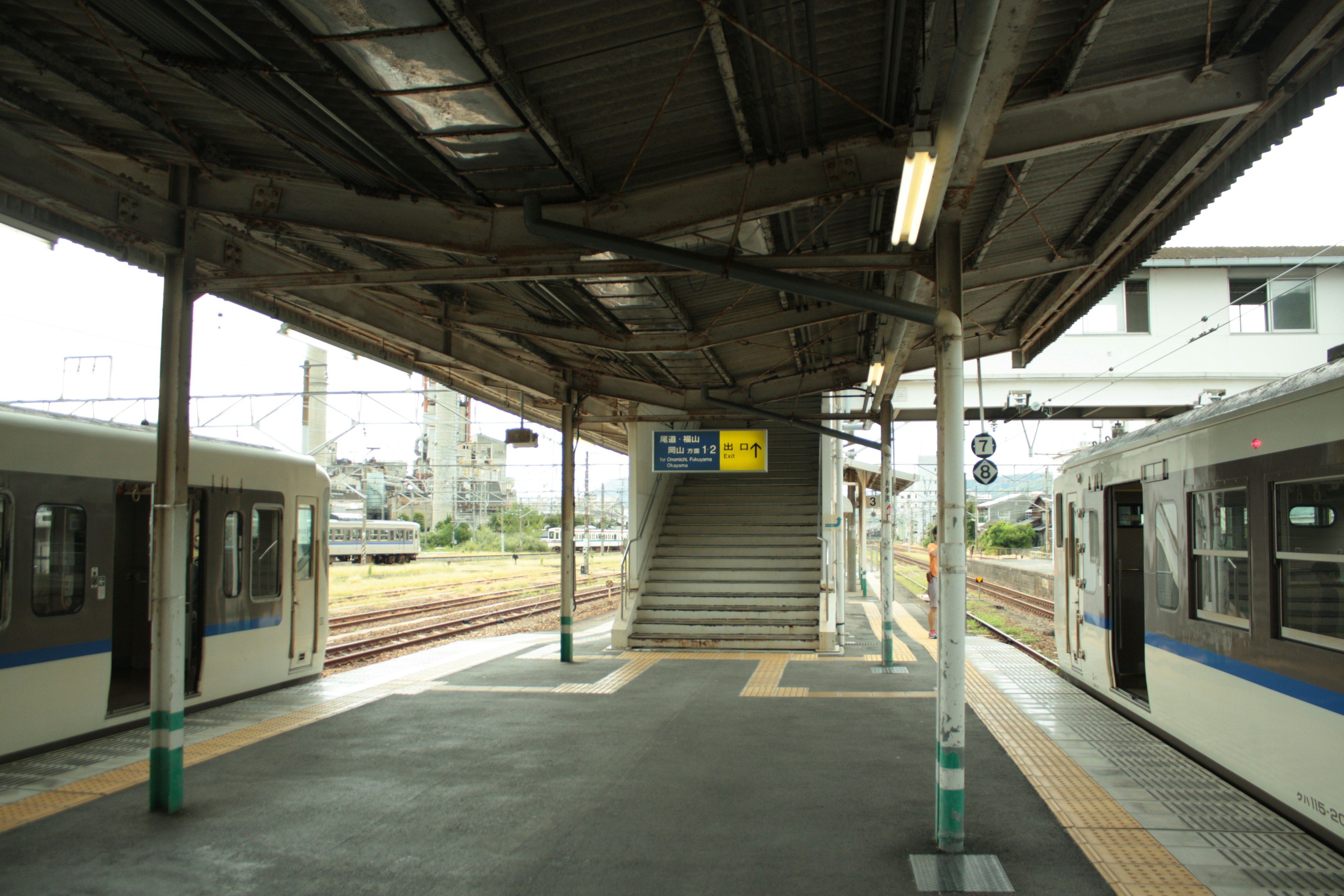 Train station platform with two trains stopped and stairs in the background