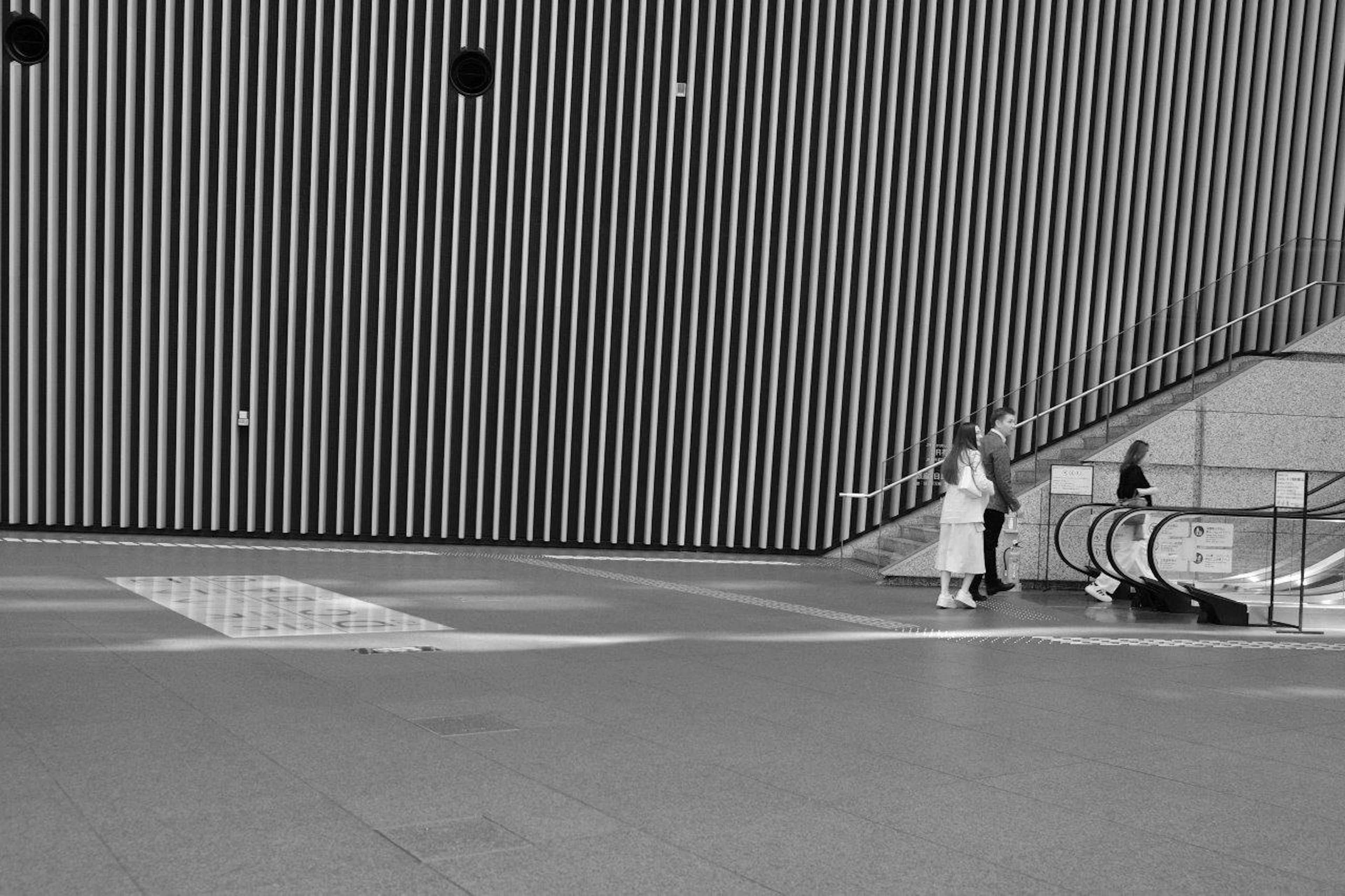 Interior en blanco y negro con personas y una pared de rayas verticales