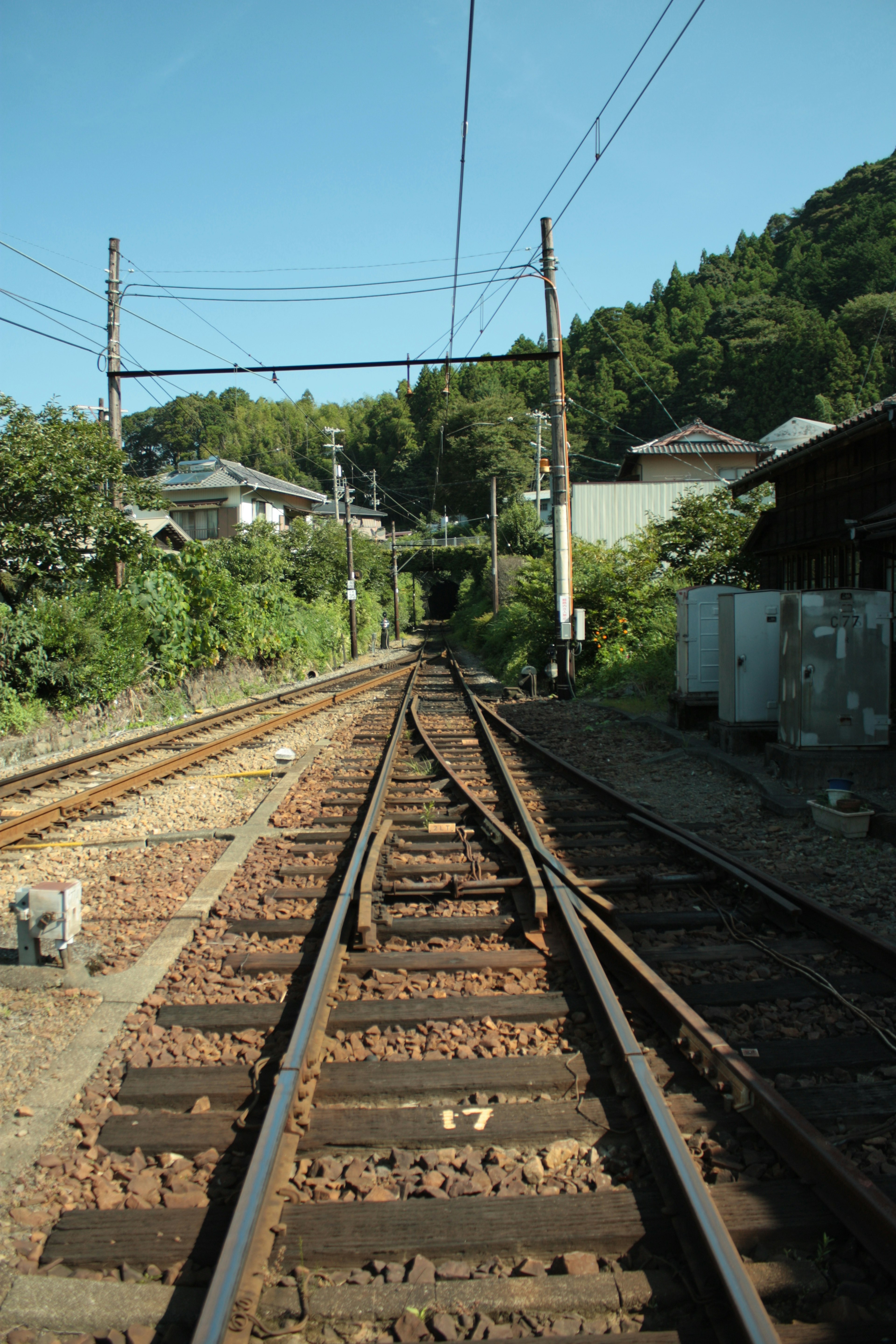 鐵路軌道延伸的風景 背景是綠色丘陵 可見房屋