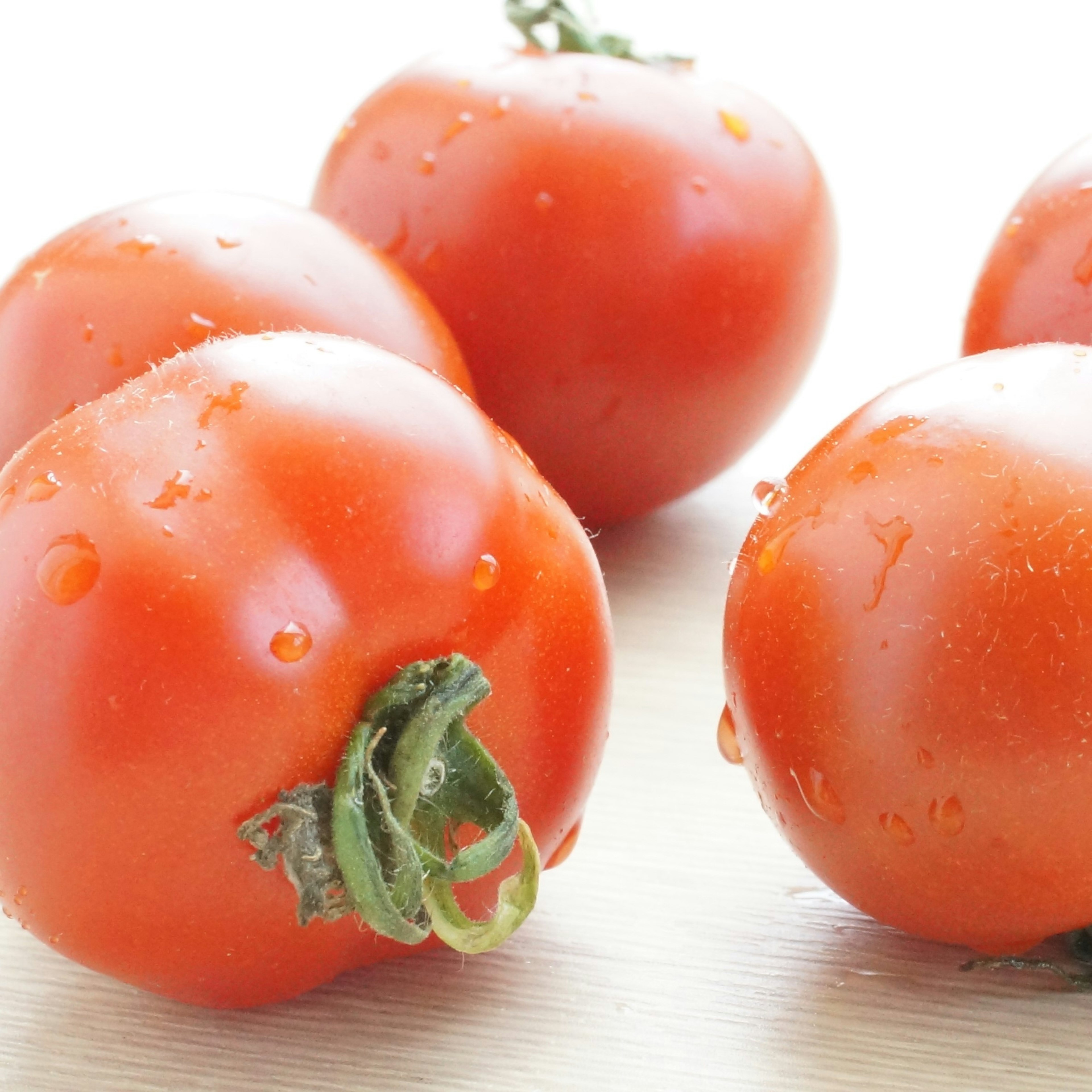 Fresh red tomatoes arranged on a light surface