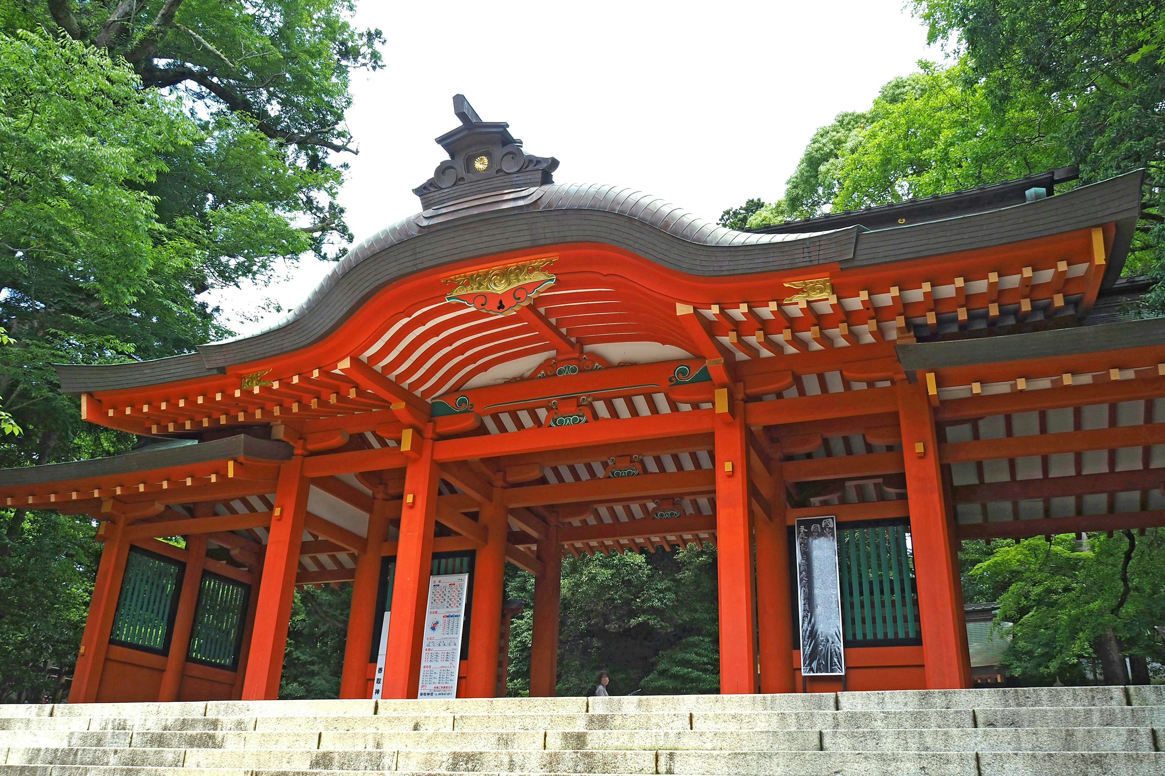 A red-roofed shrine building surrounded by green trees