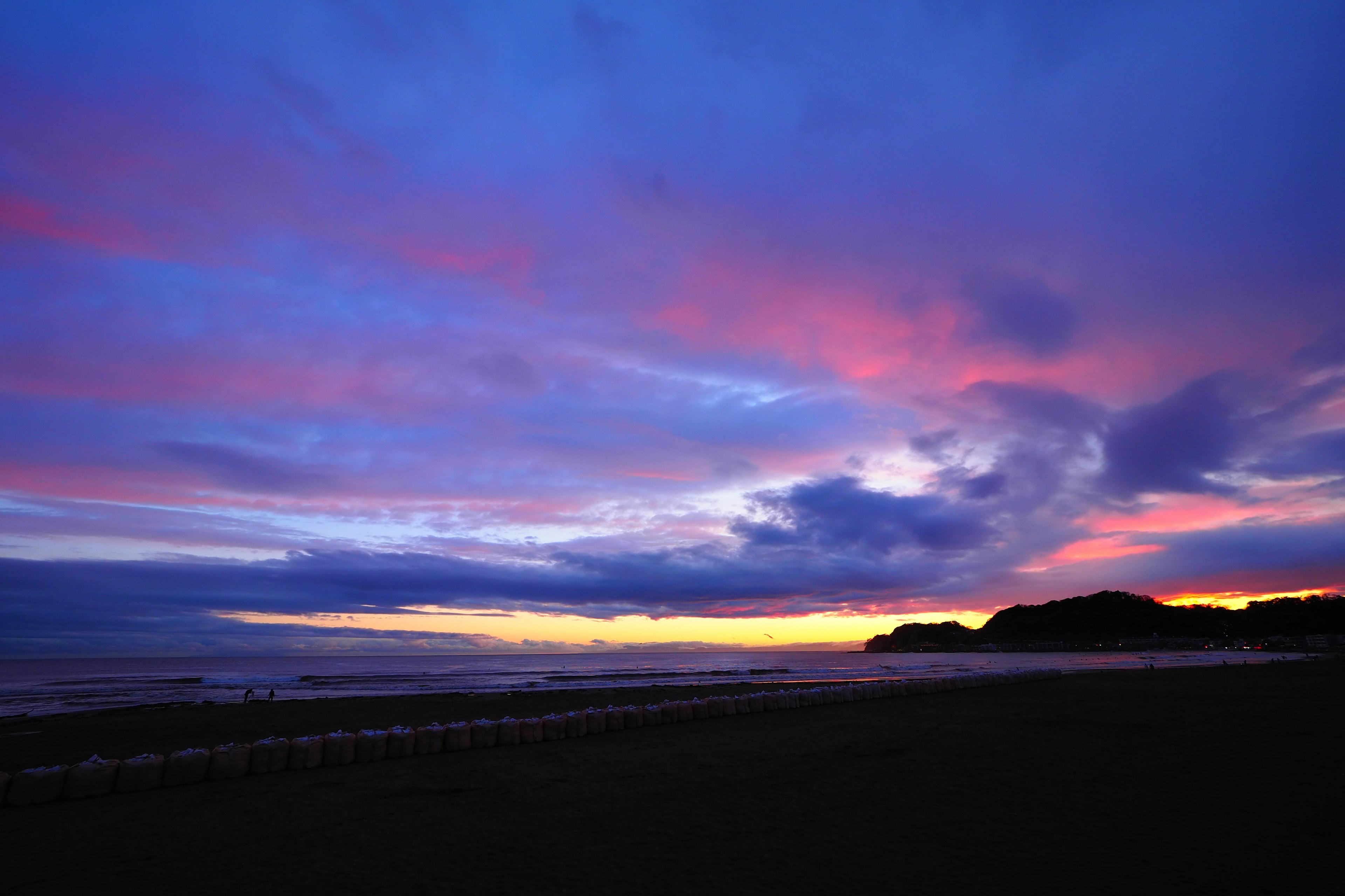 海岸日落景色，紫色和橙色的天空，漂浮的雲朵