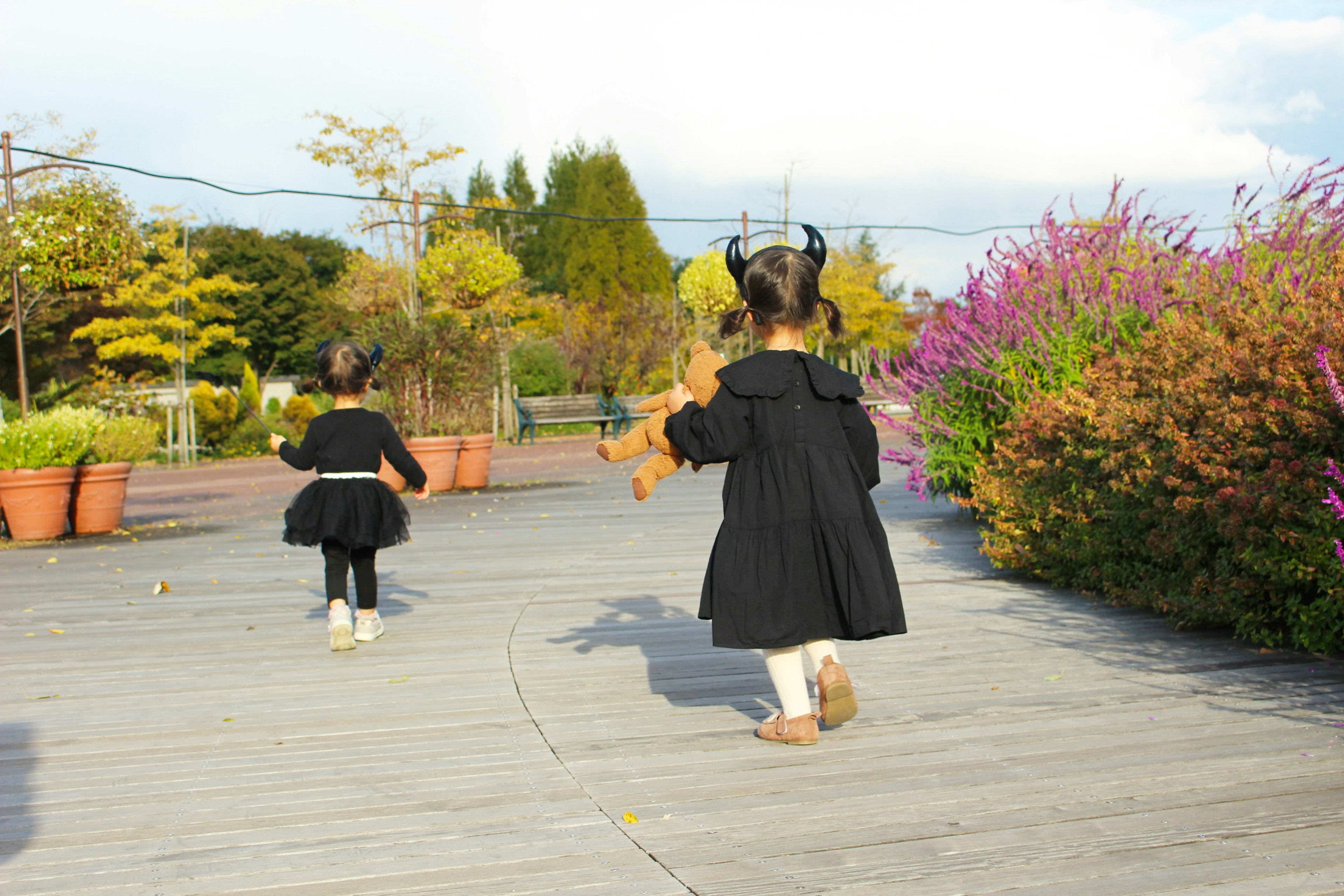 二人の子供が黒いドレスを着て公園を歩いている