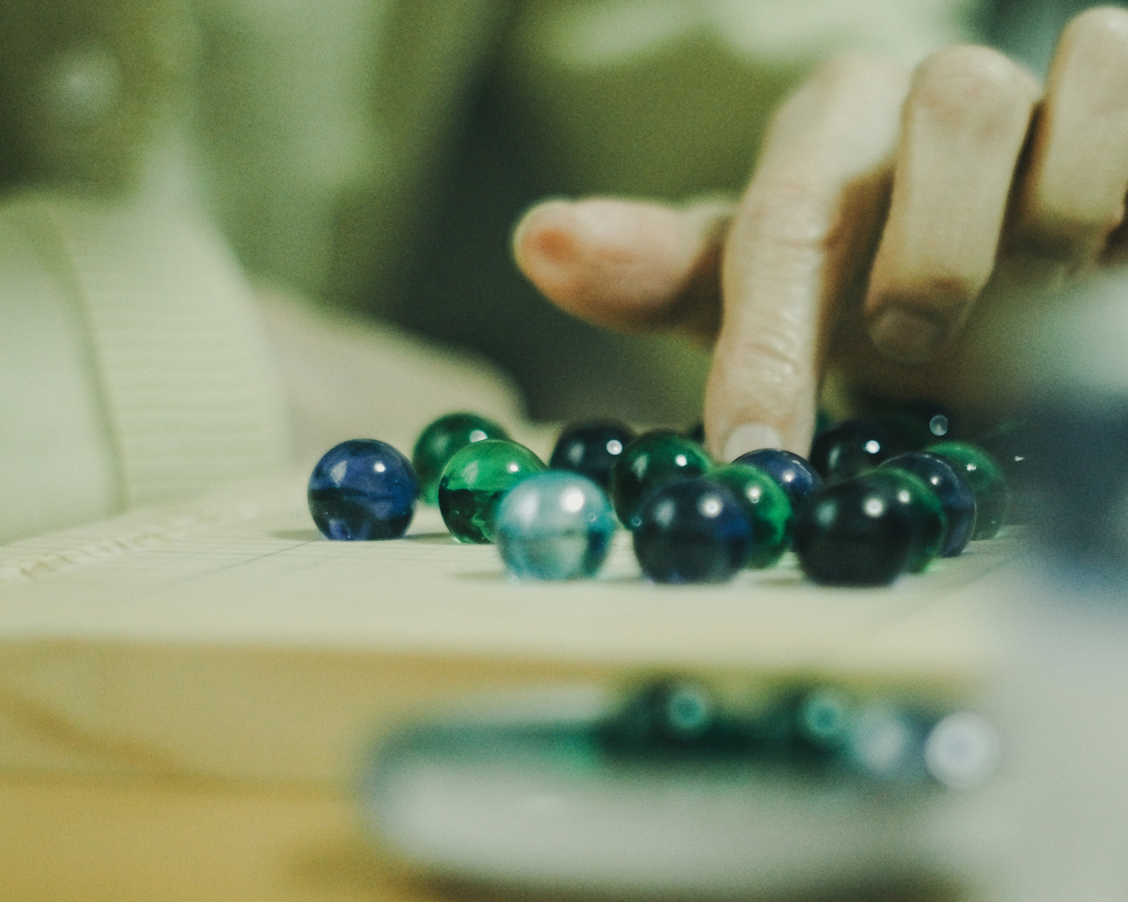 A hand touching colorful marbles on a wooden surface