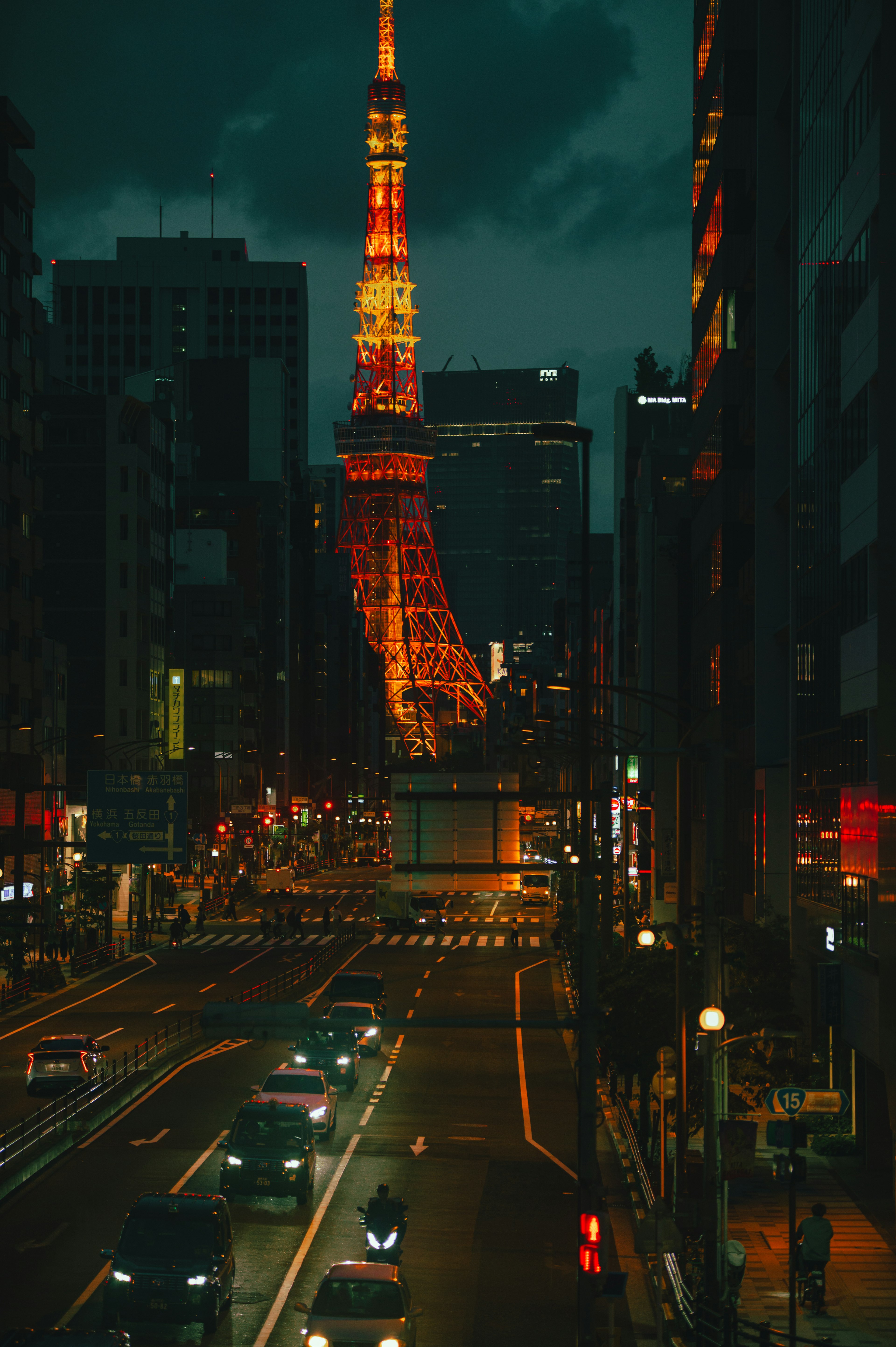 Tour de Tokyo illuminée la nuit avec une rue animée et des voitures