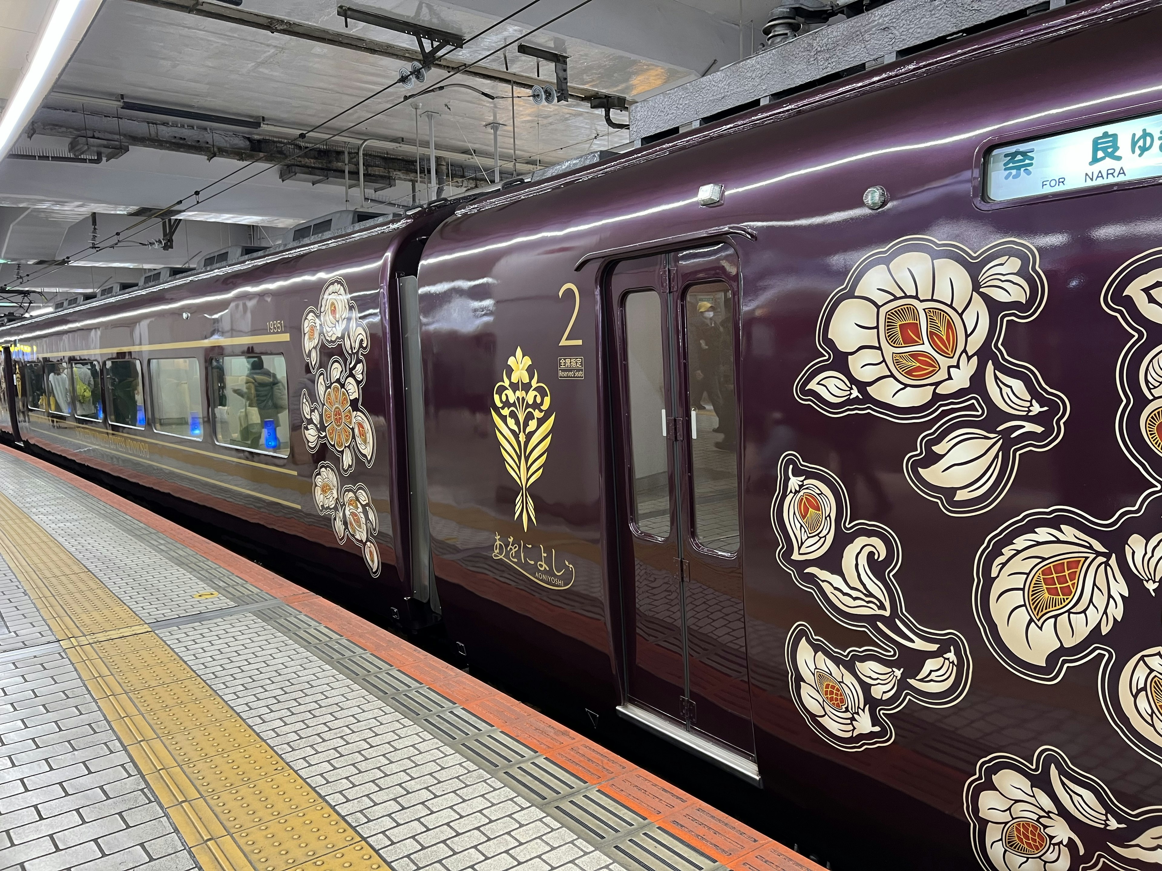 紫色の装飾的な列車が駅に停車中で、花の模様が描かれている