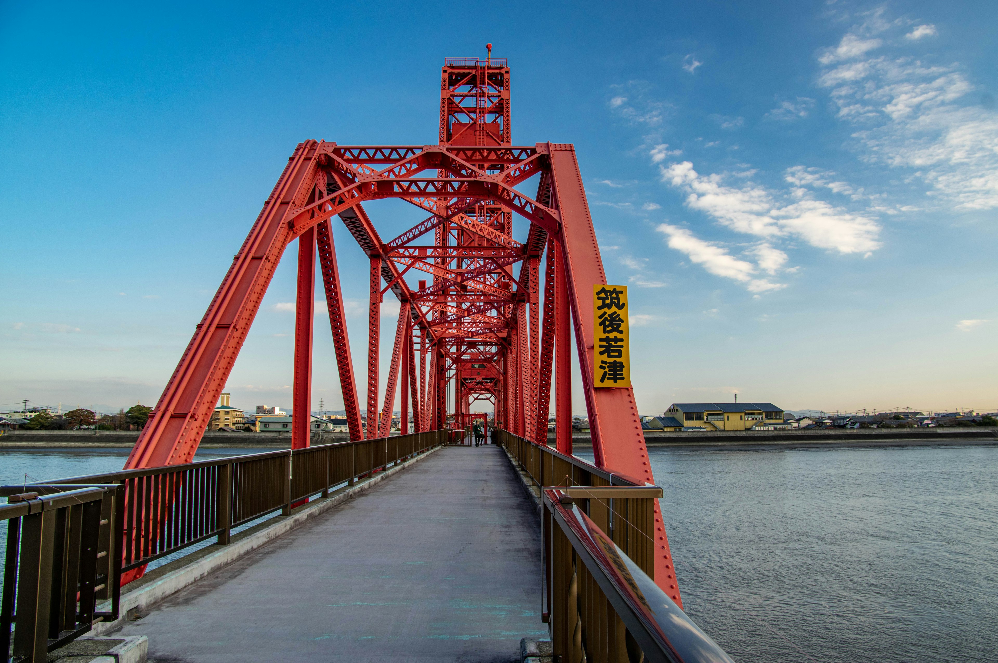 红色桥梁横跨河流，蓝天映衬