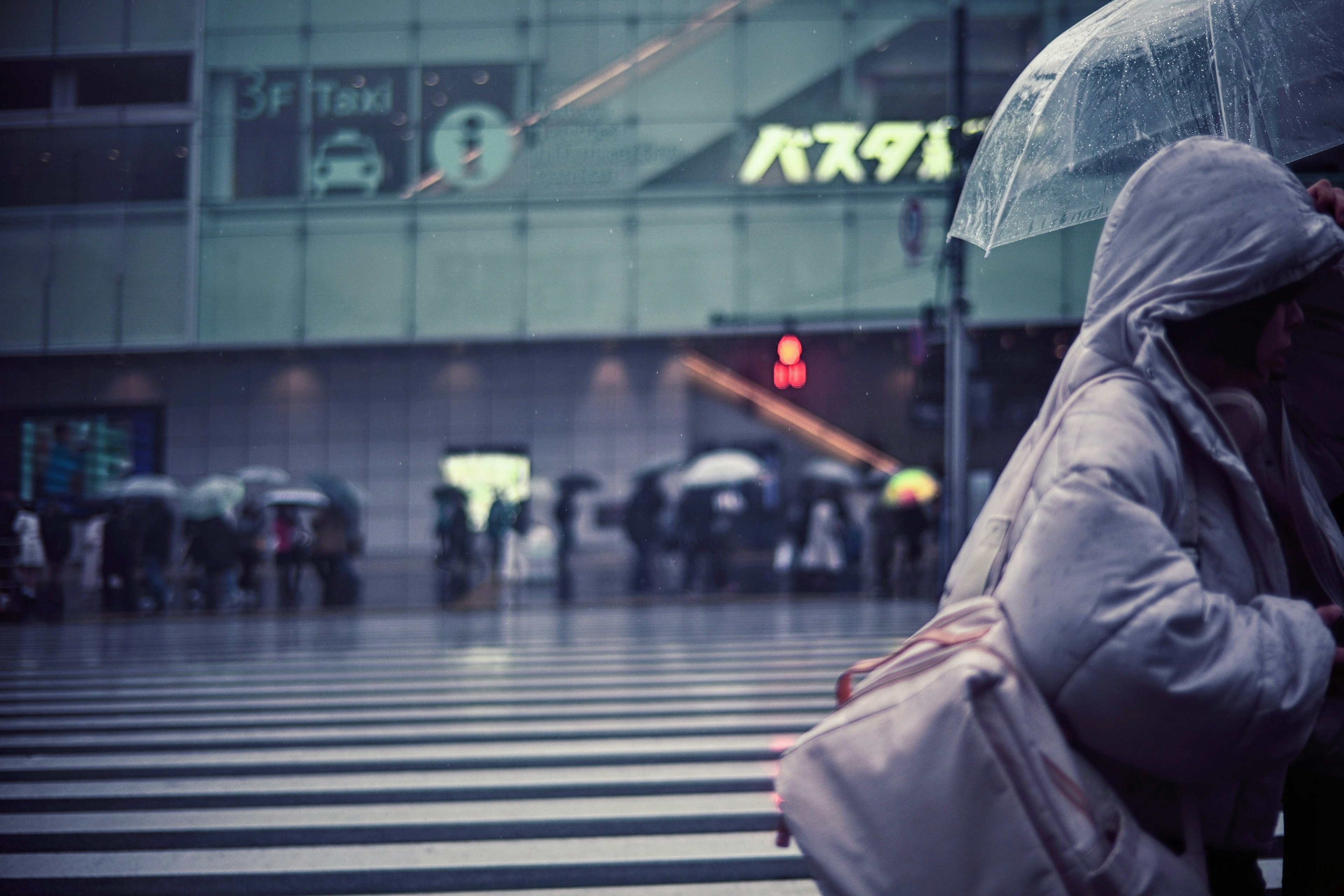 Scène urbaine avec des personnes traversant la rue sous des parapluies sous la pluie