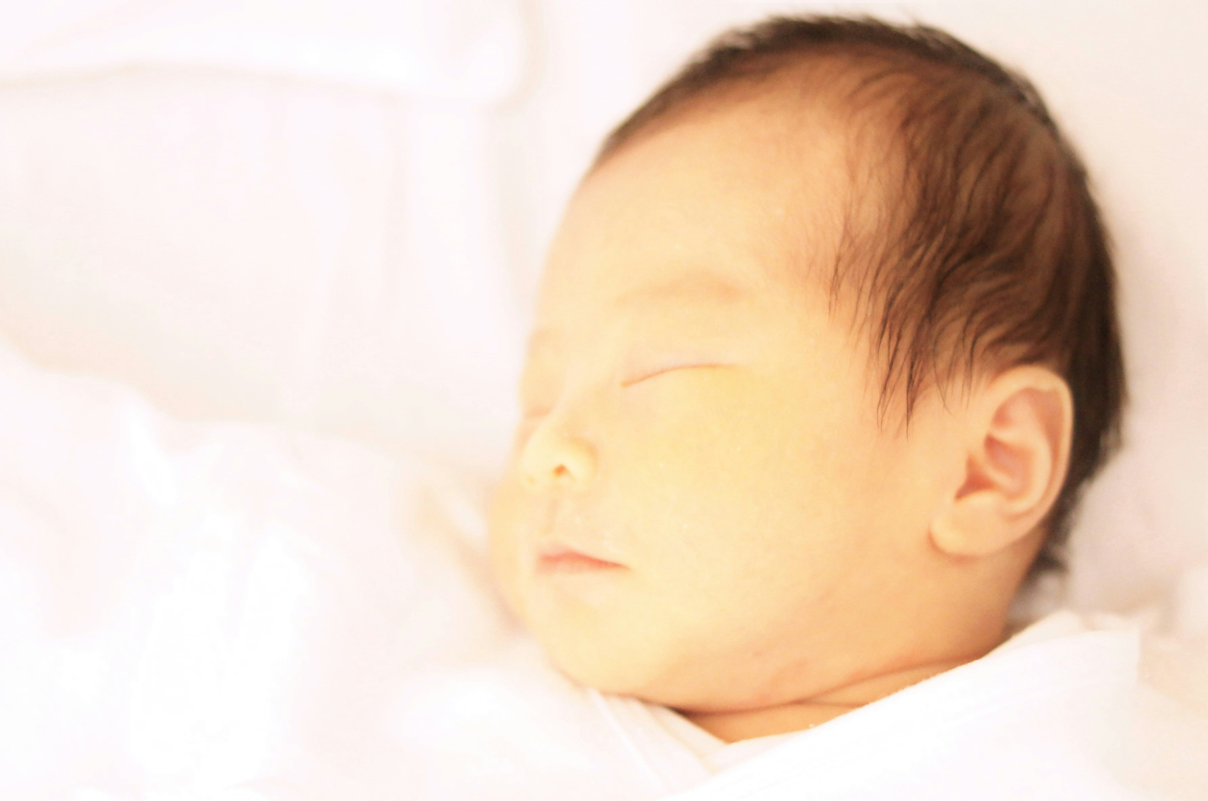 A sleeping baby wrapped in soft white fabric