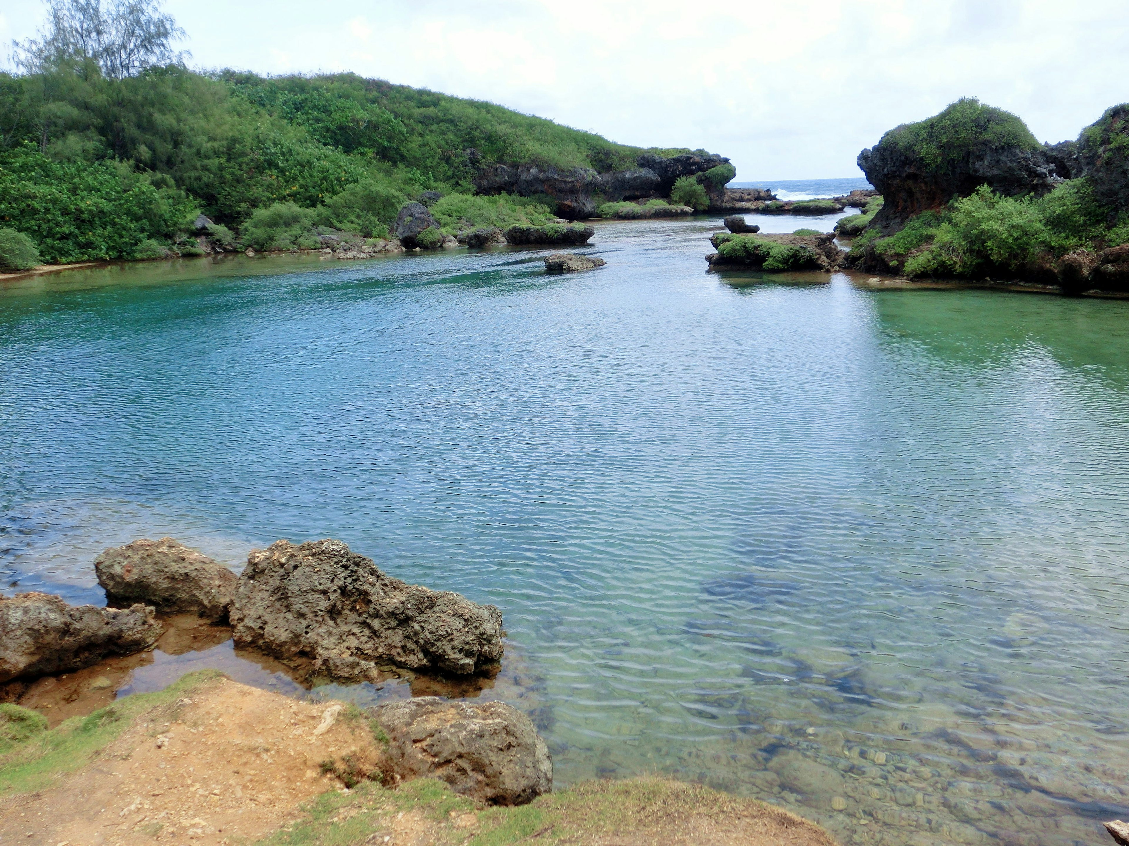 Eaux sereines avec collines vertes et formations rocheuses