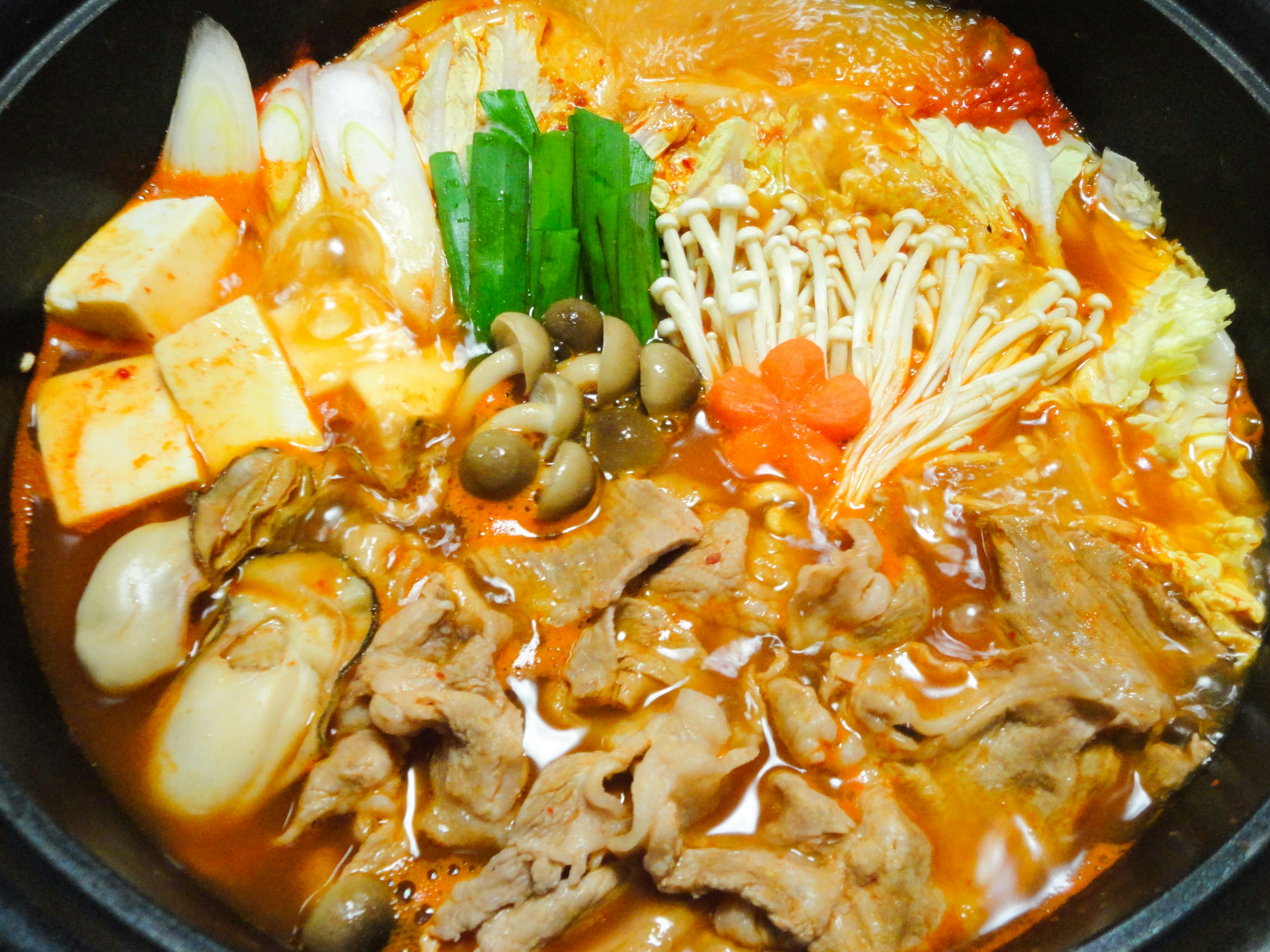 Un plato de fondue caliente con carne y varias verduras