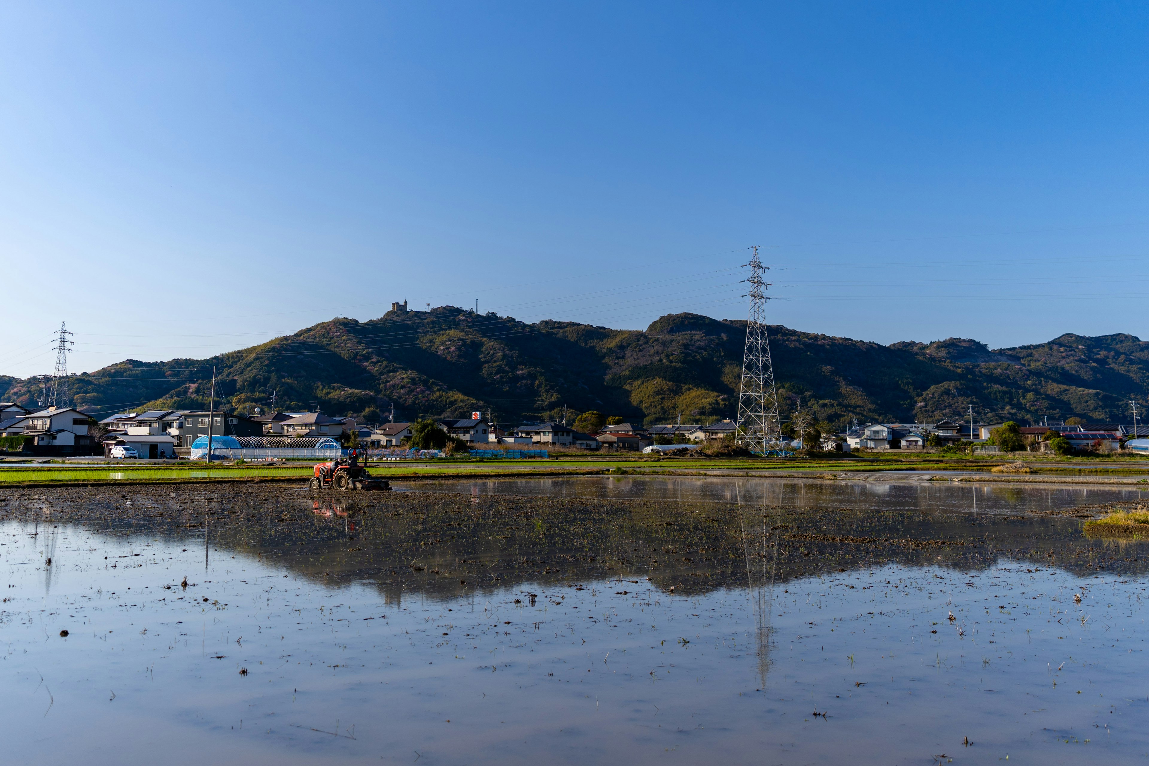 稻田和山脈的景觀，帶有電塔