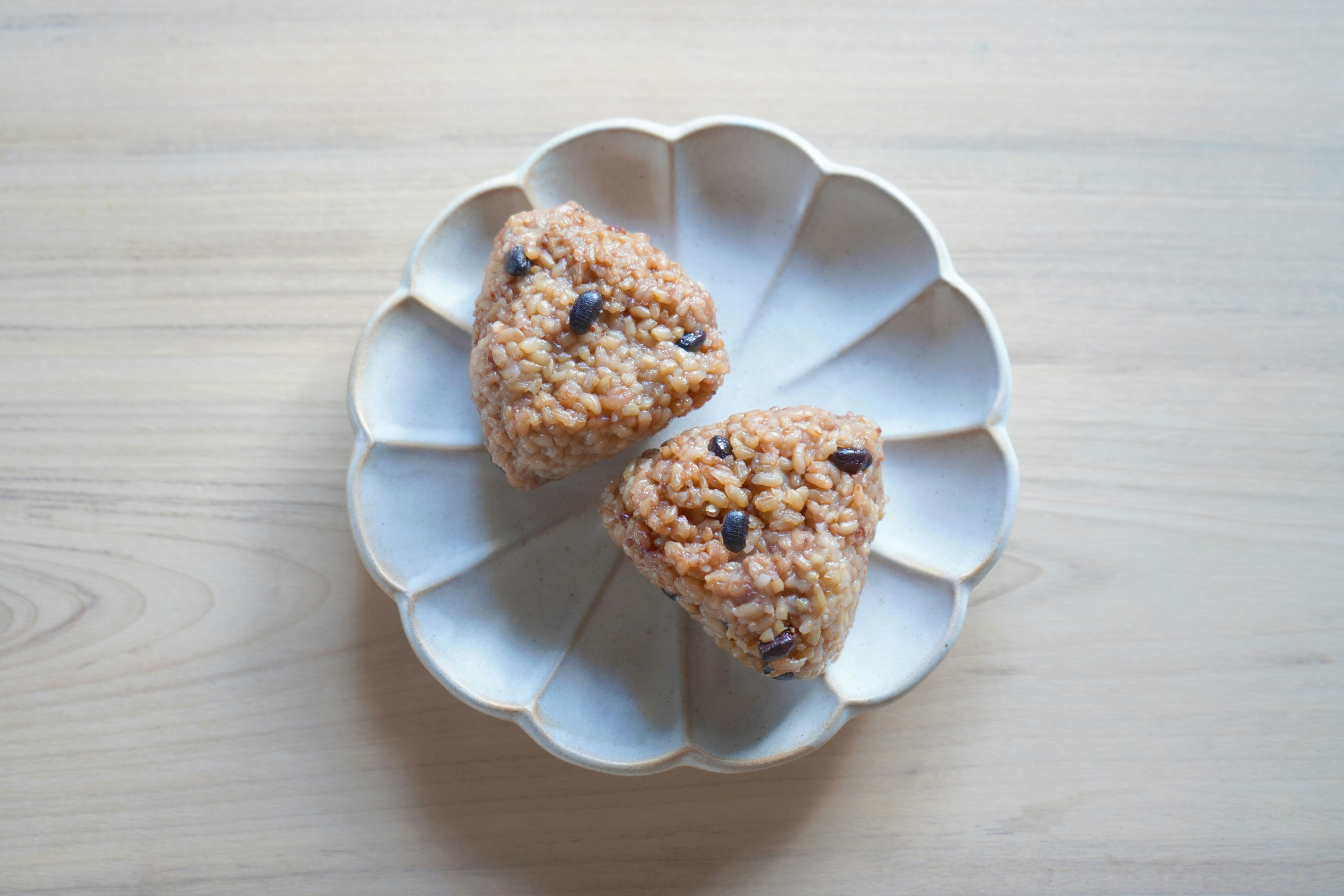 Two triangular rice balls on a white plate