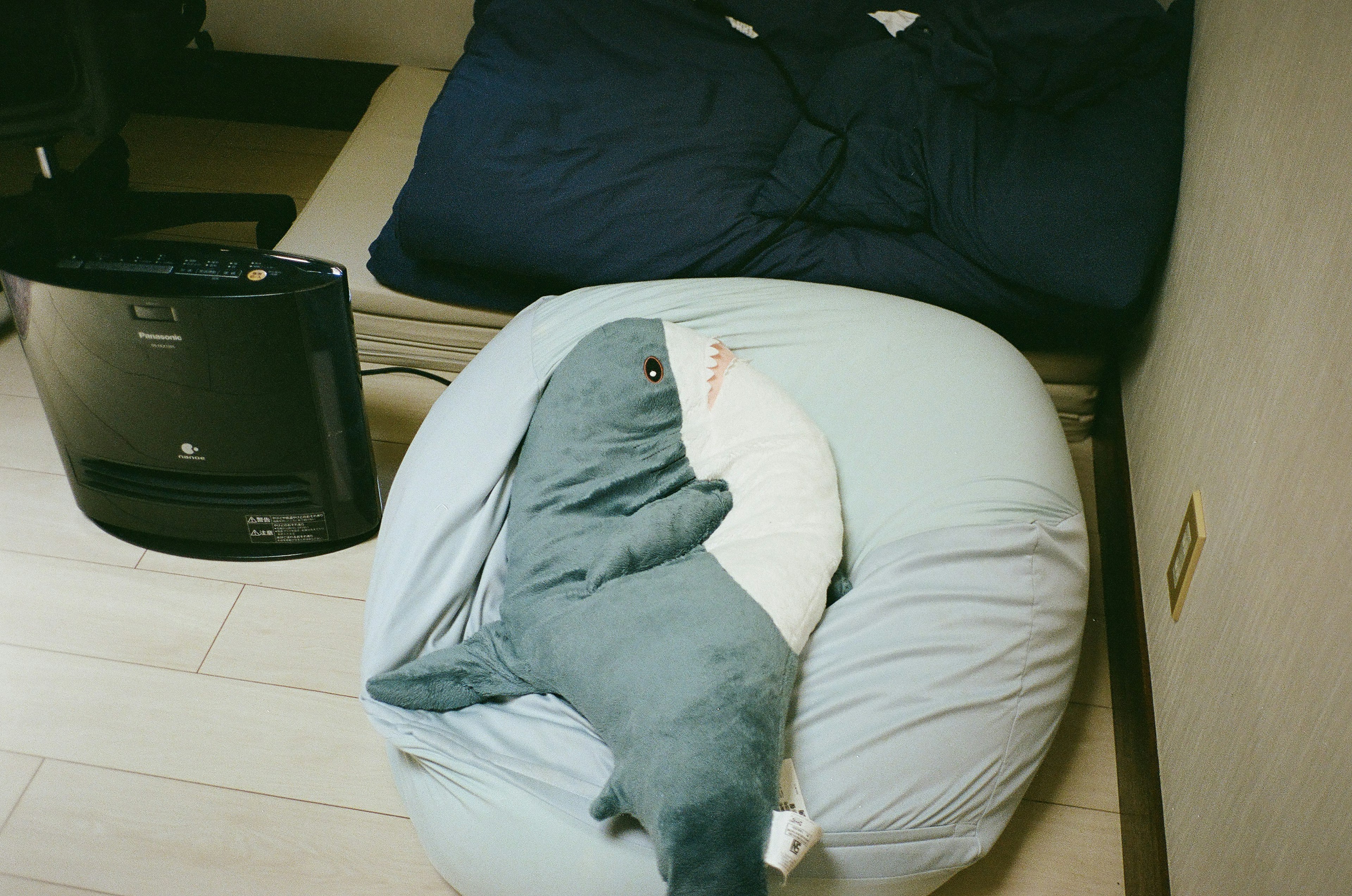 Shark-shaped plush toy on a light blue cushion in a cozy room