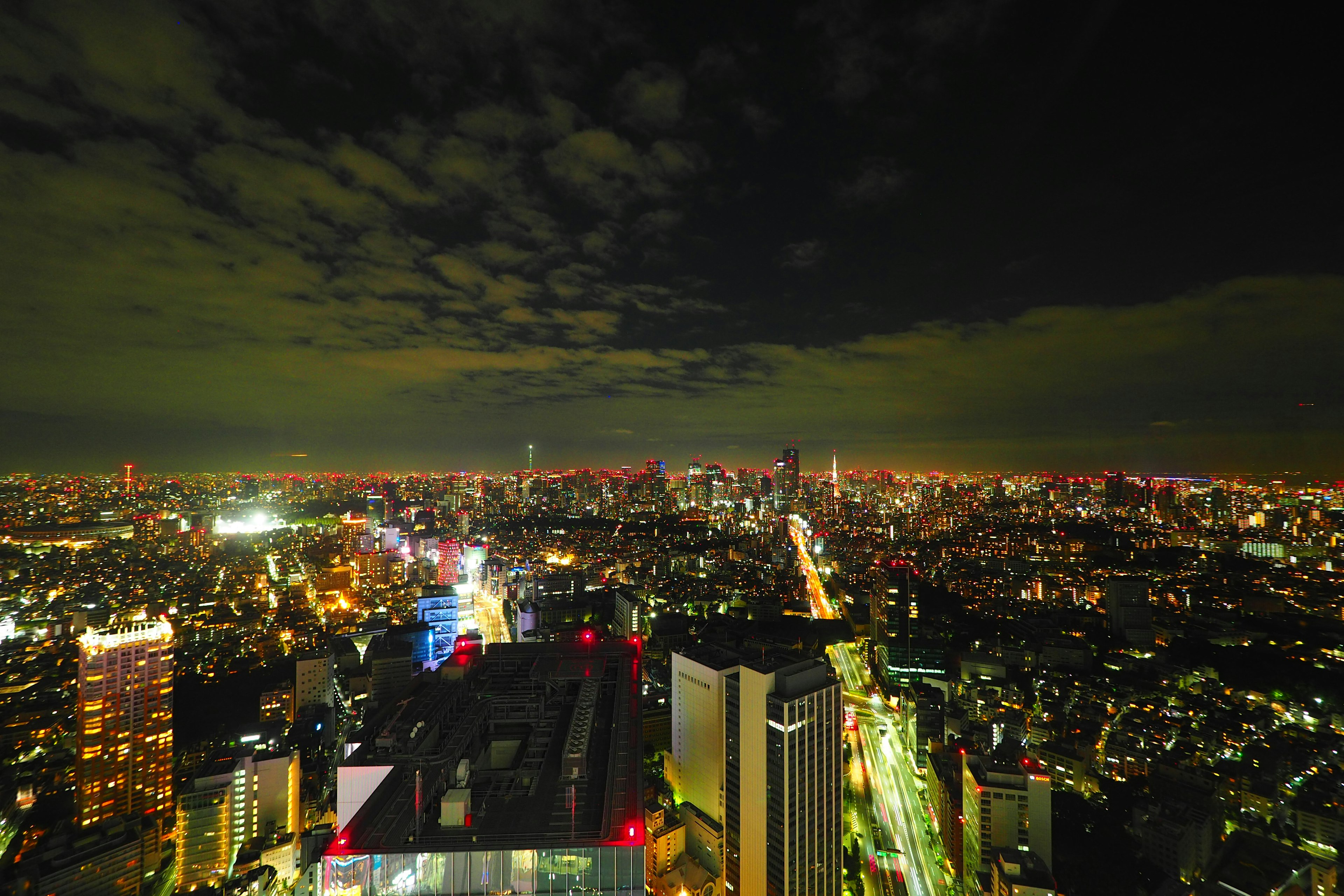 Tokyo night skyline featuring illuminated skyscrapers and a cloudy sky