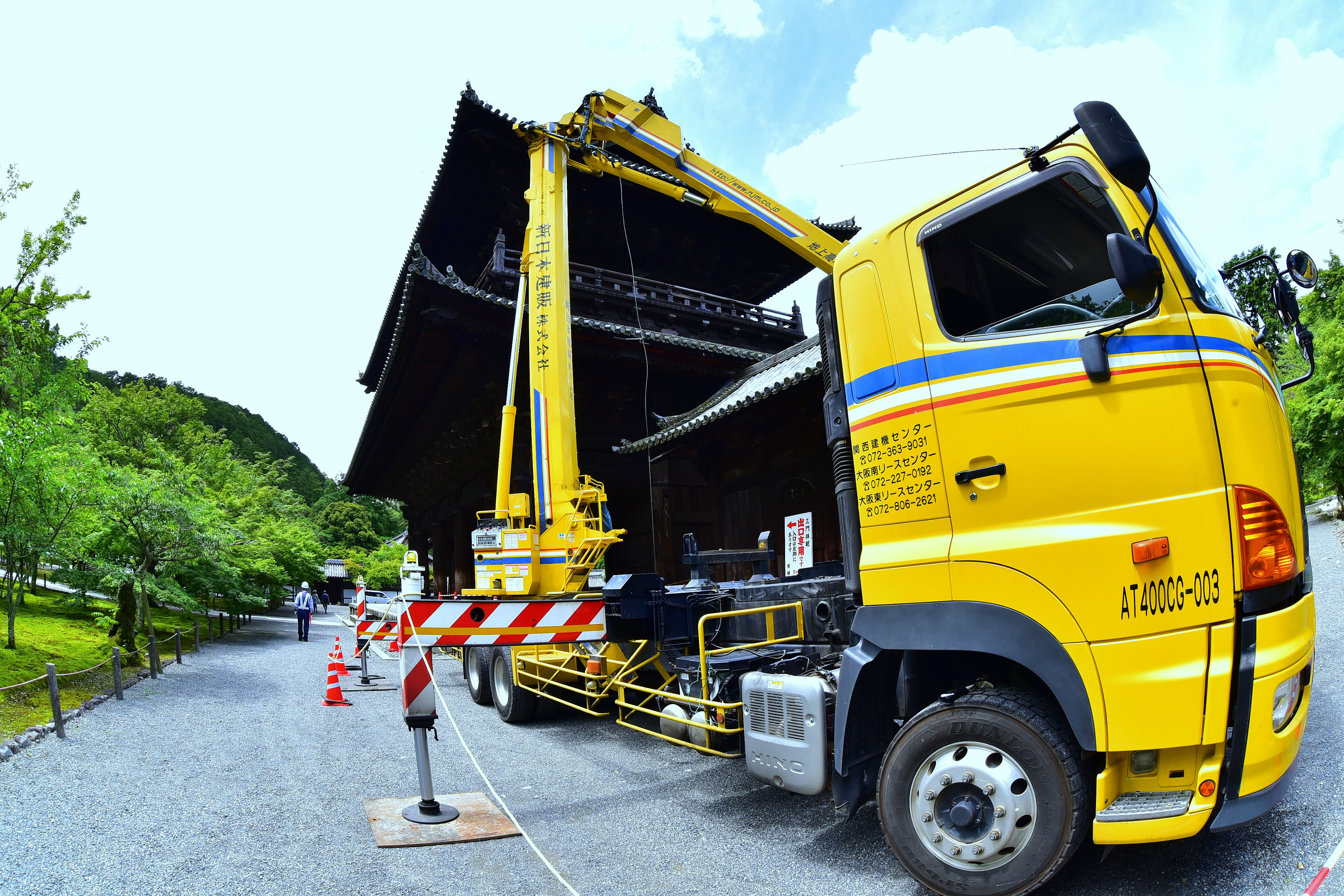 Un camion jaune en train de monter une scène entourée de verdure