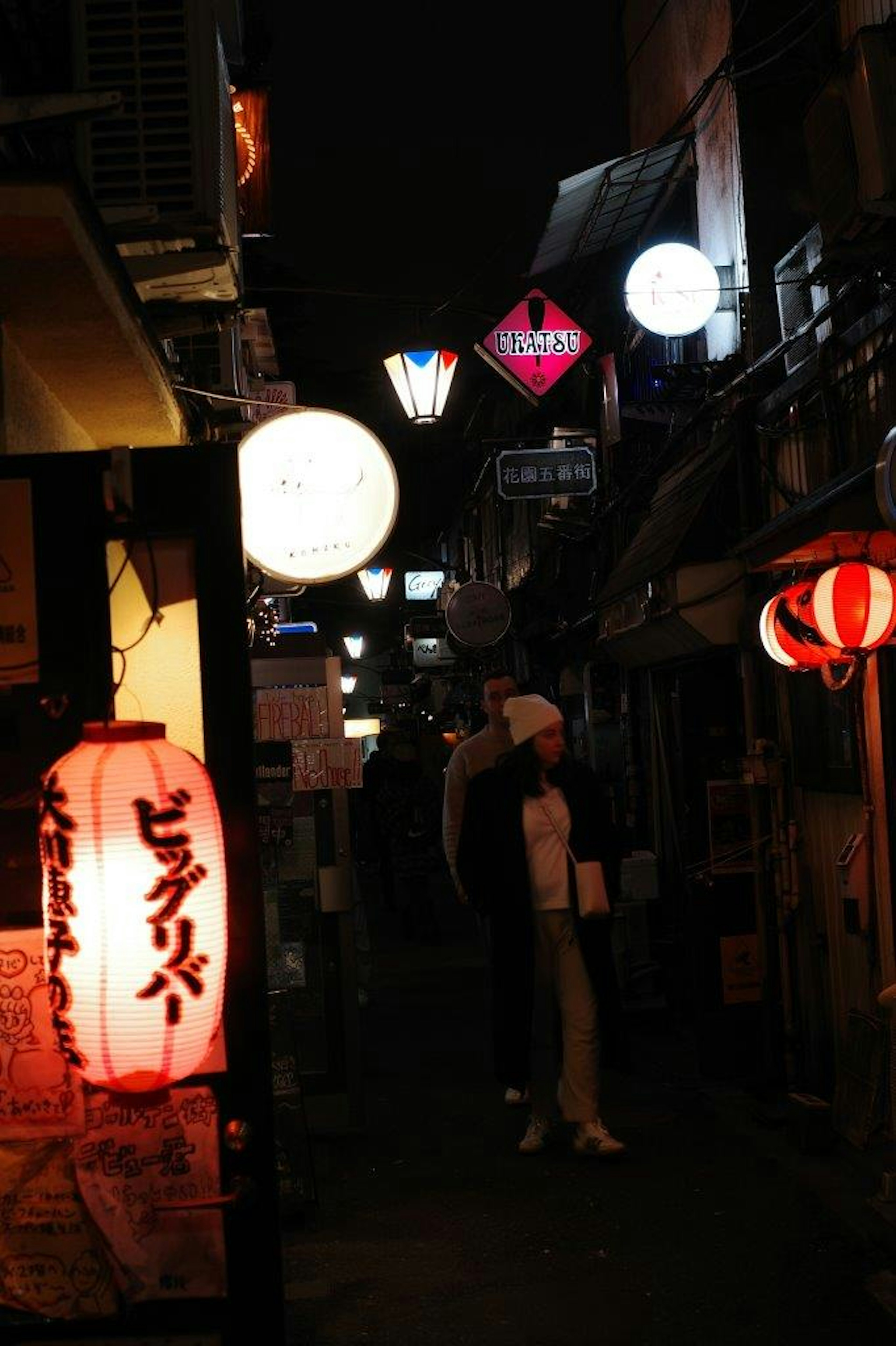 夜の小道に並ぶ提灯とネオンの看板