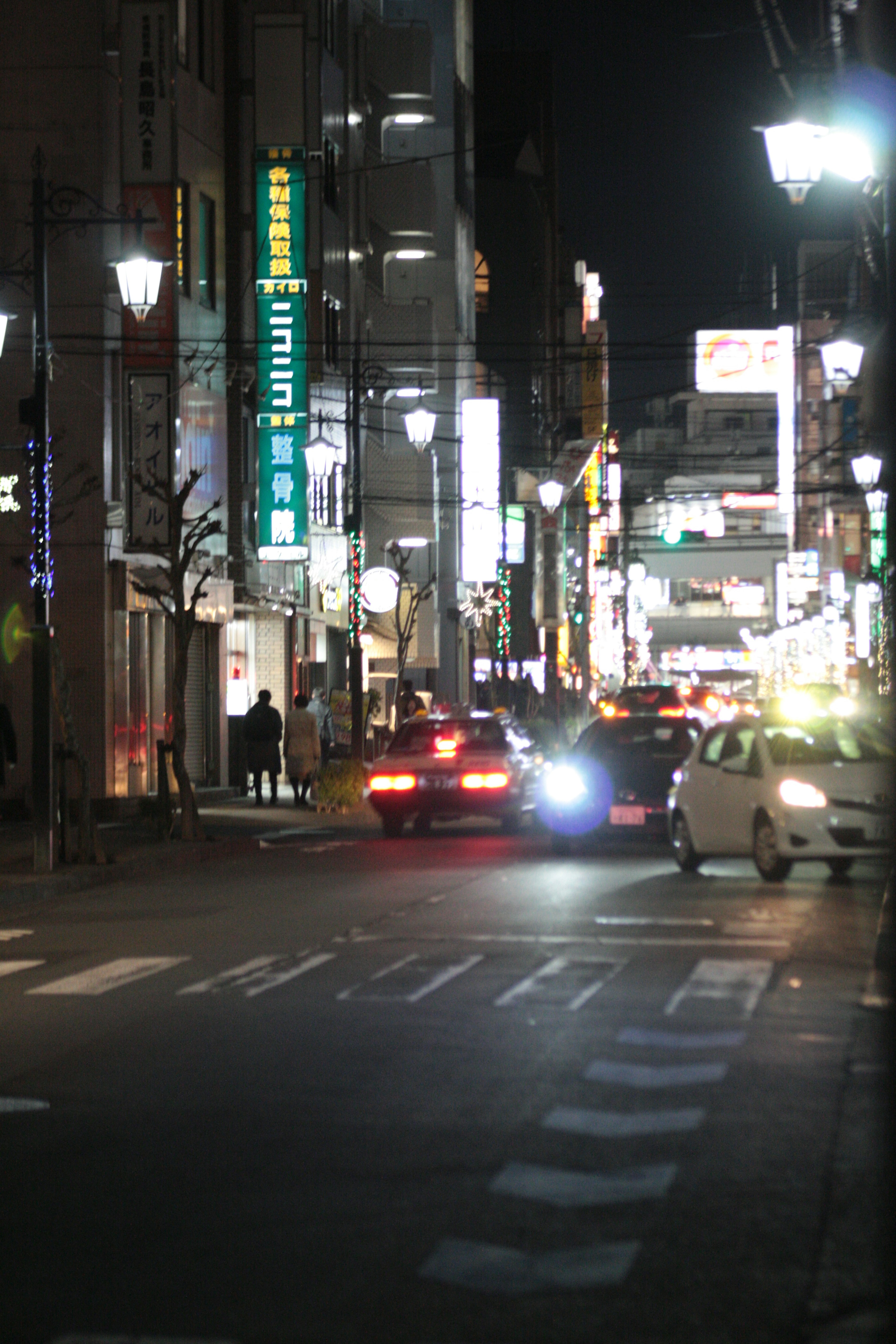 Night street scene with cars and neon signs