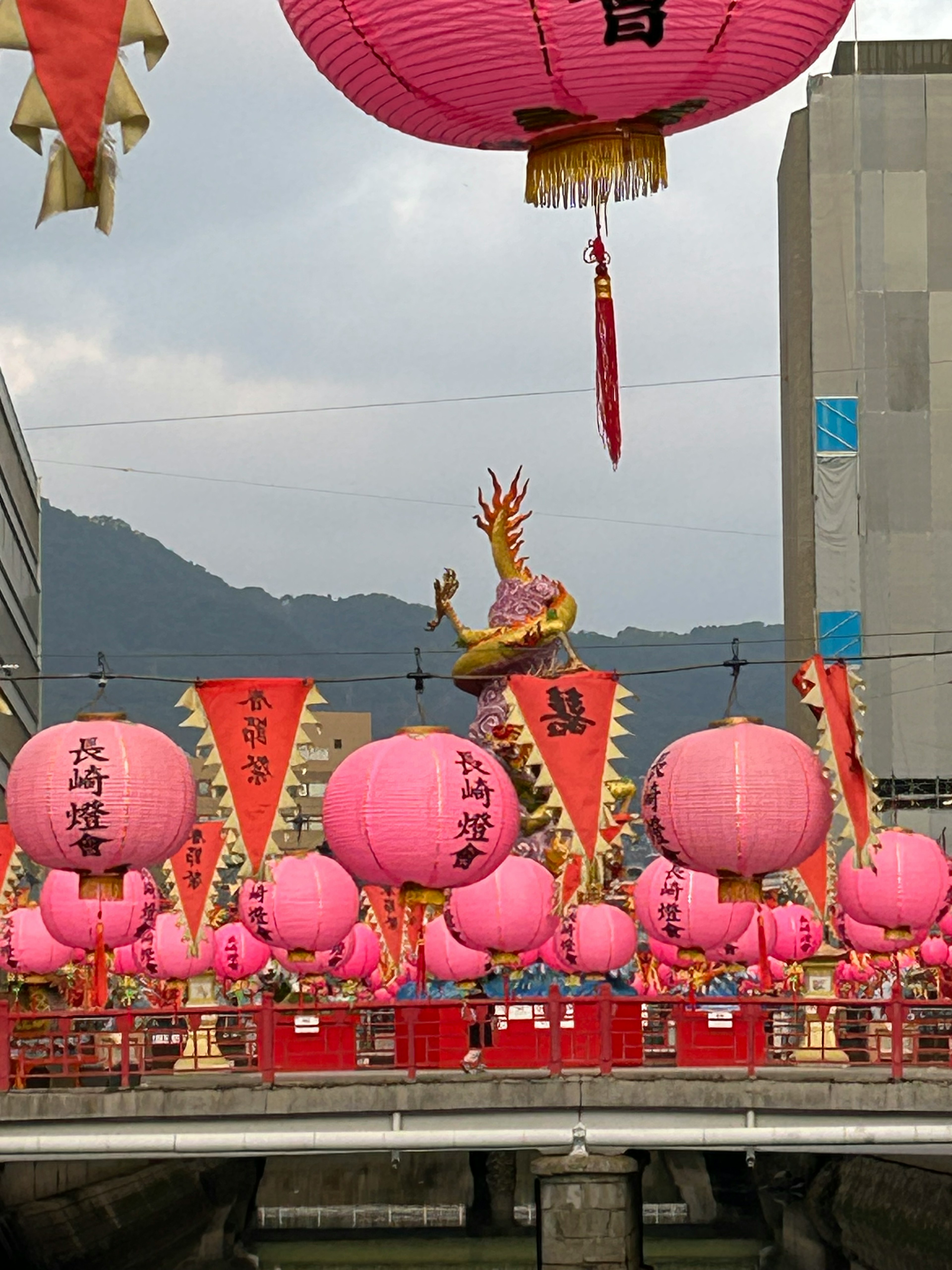 Festival scene with pink lanterns and a decorative dragon in the background