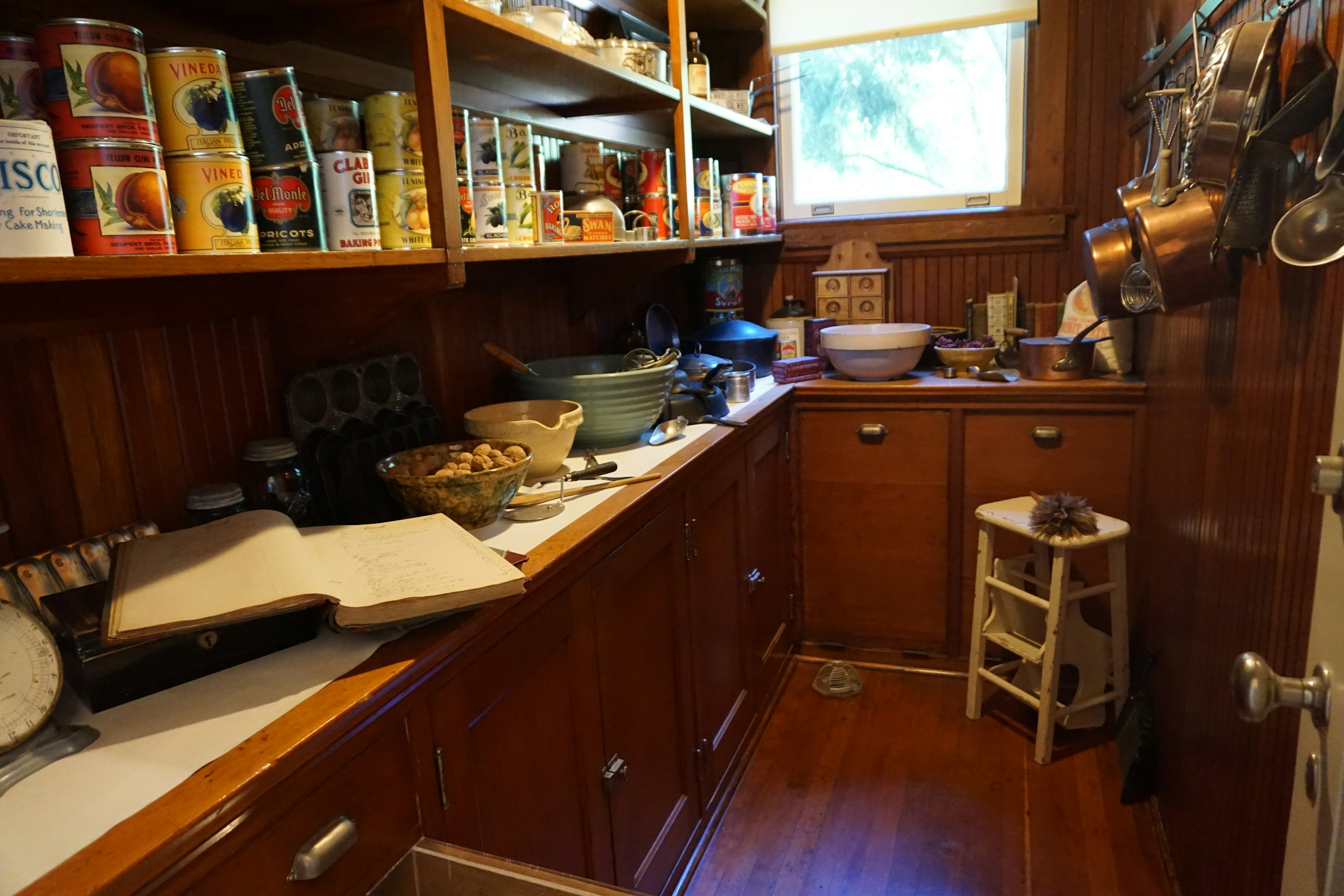 Narrow kitchen counter with cooking utensils and shelves of canned goods