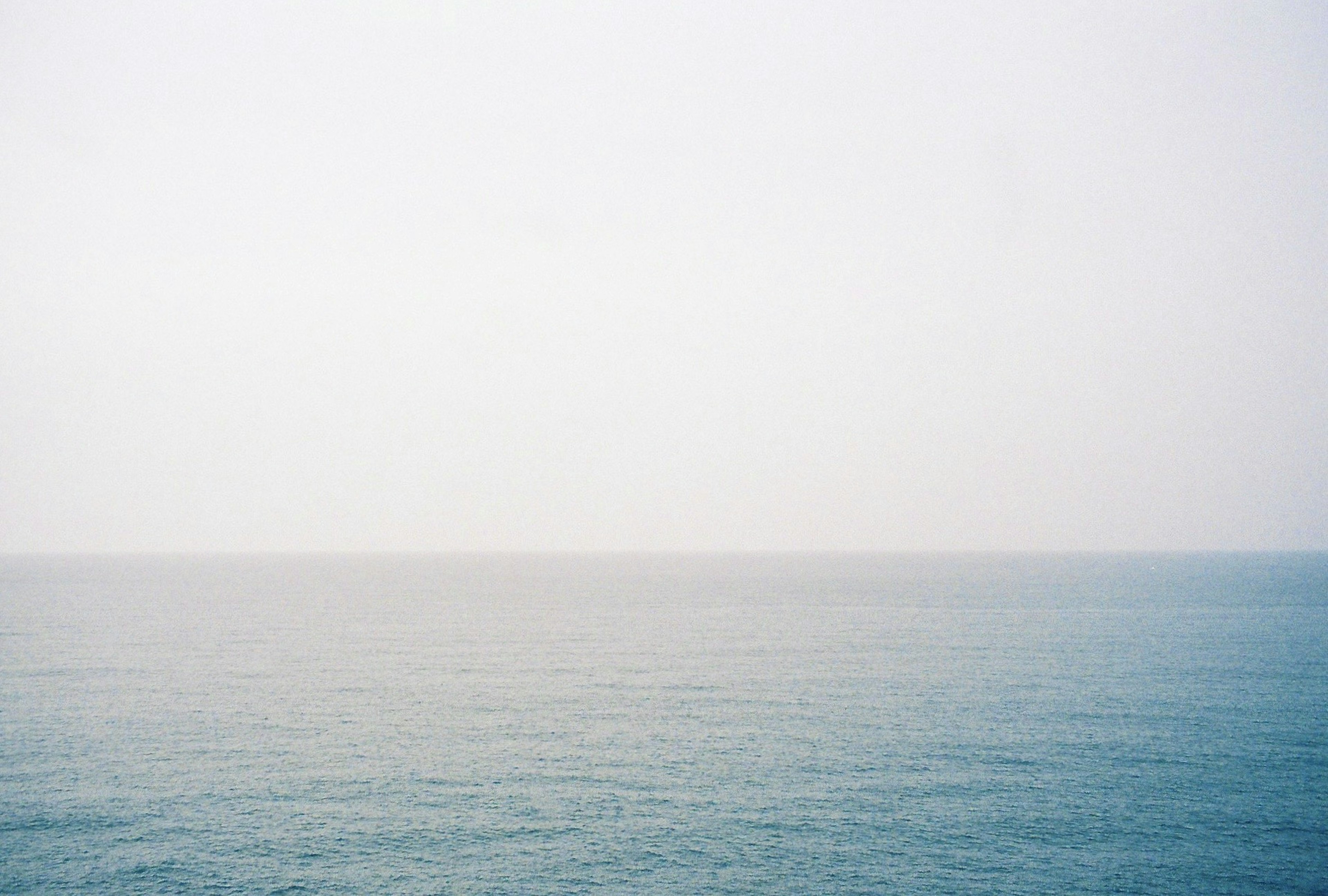 A serene view of the ocean and sky merging into a soft horizon