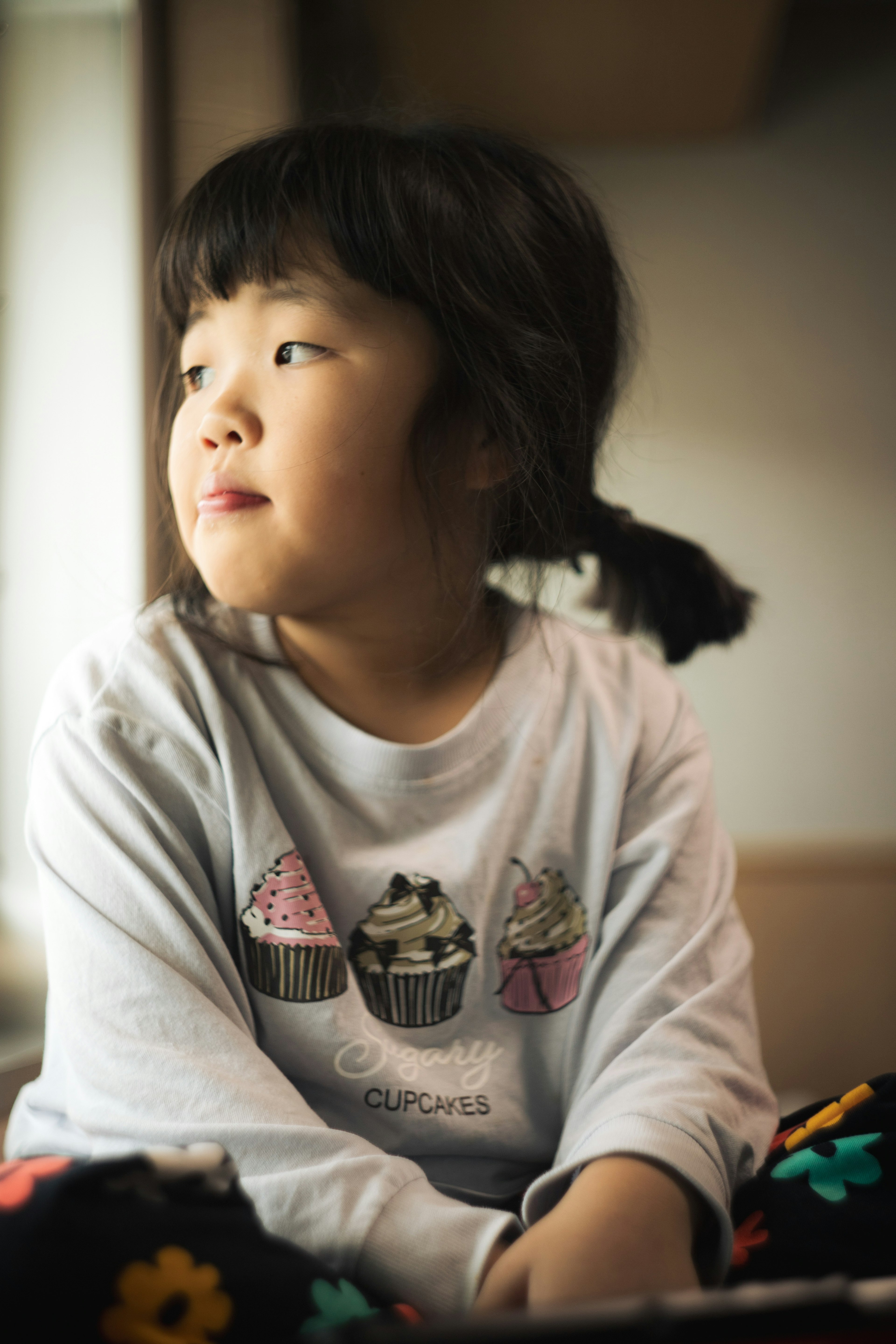 Child wearing a cupcake design t-shirt looking to the side