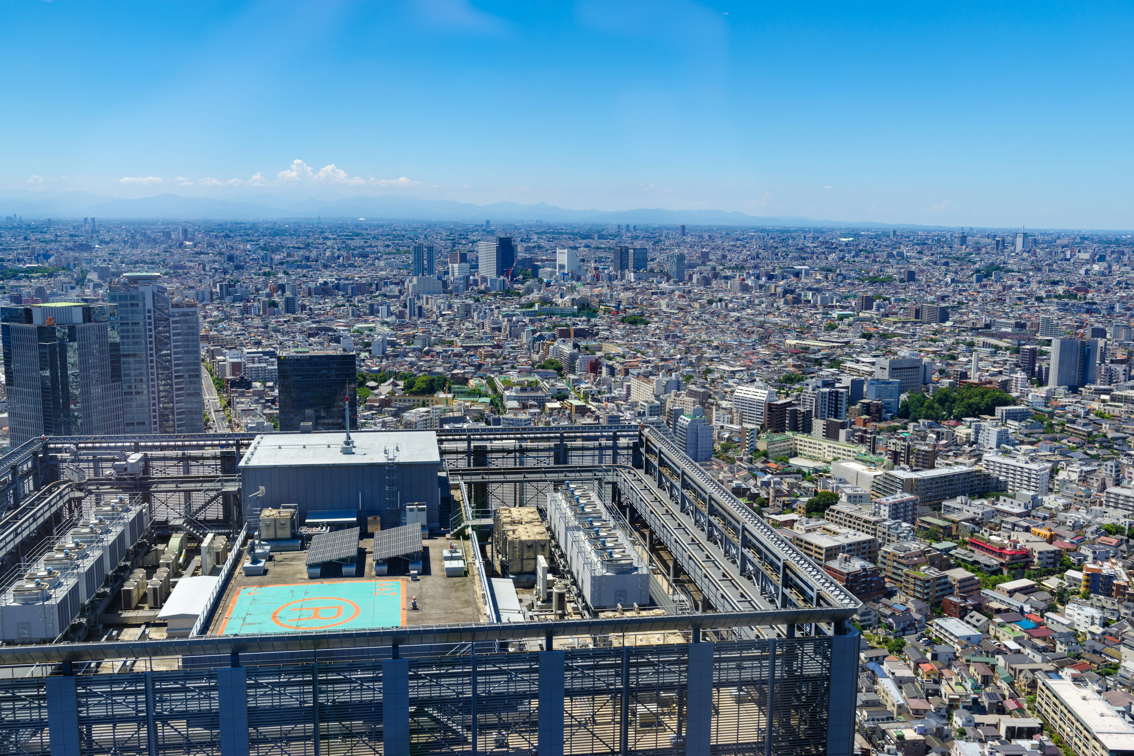 Vista desde la azotea de un rascacielos en Tokio paisaje urbano expansivo cielo azul y montañas distantes